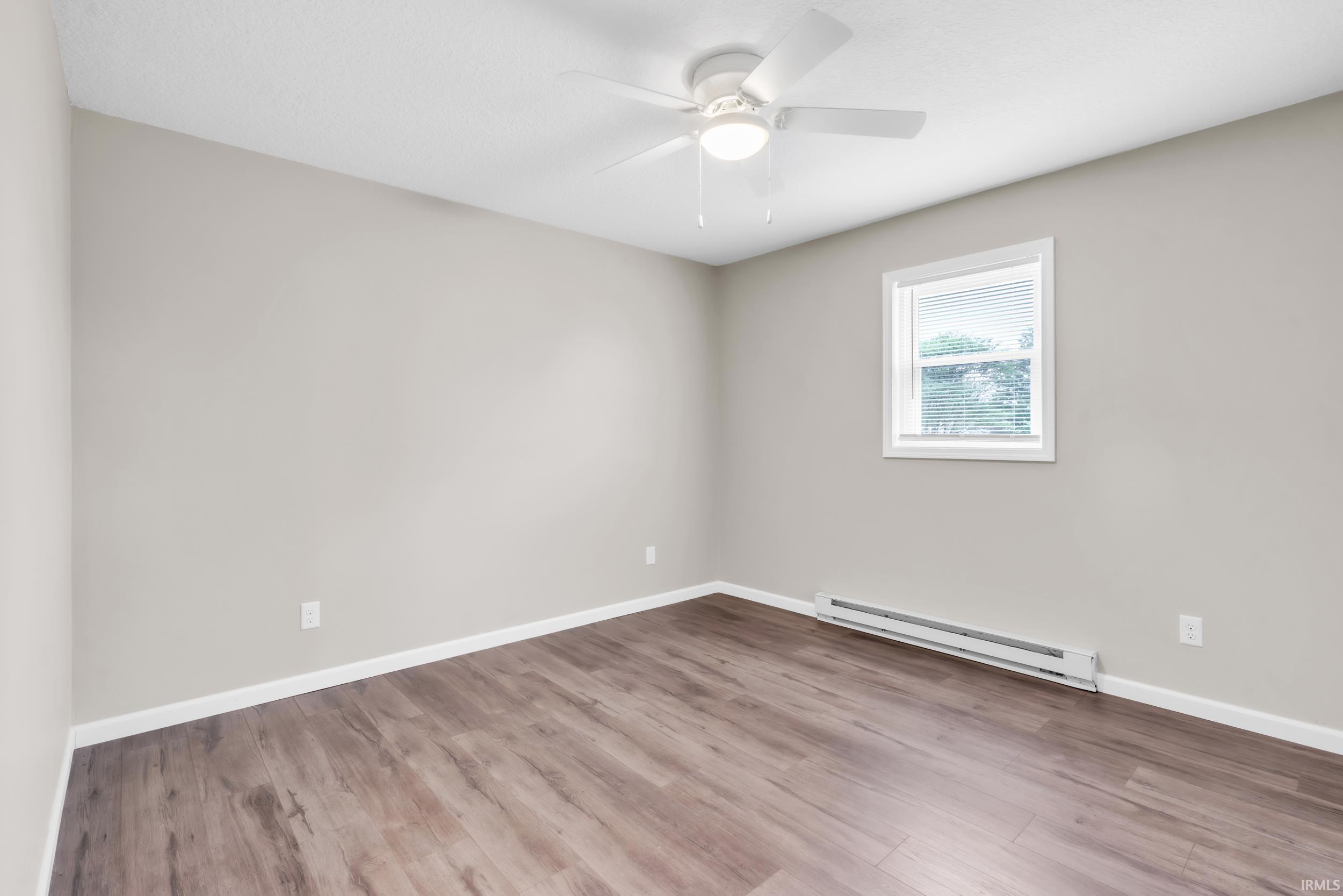 Room featuring wood-finish flooring, a window with blinds, a ceiling fan with integrated lighting, and neutral wall tones
