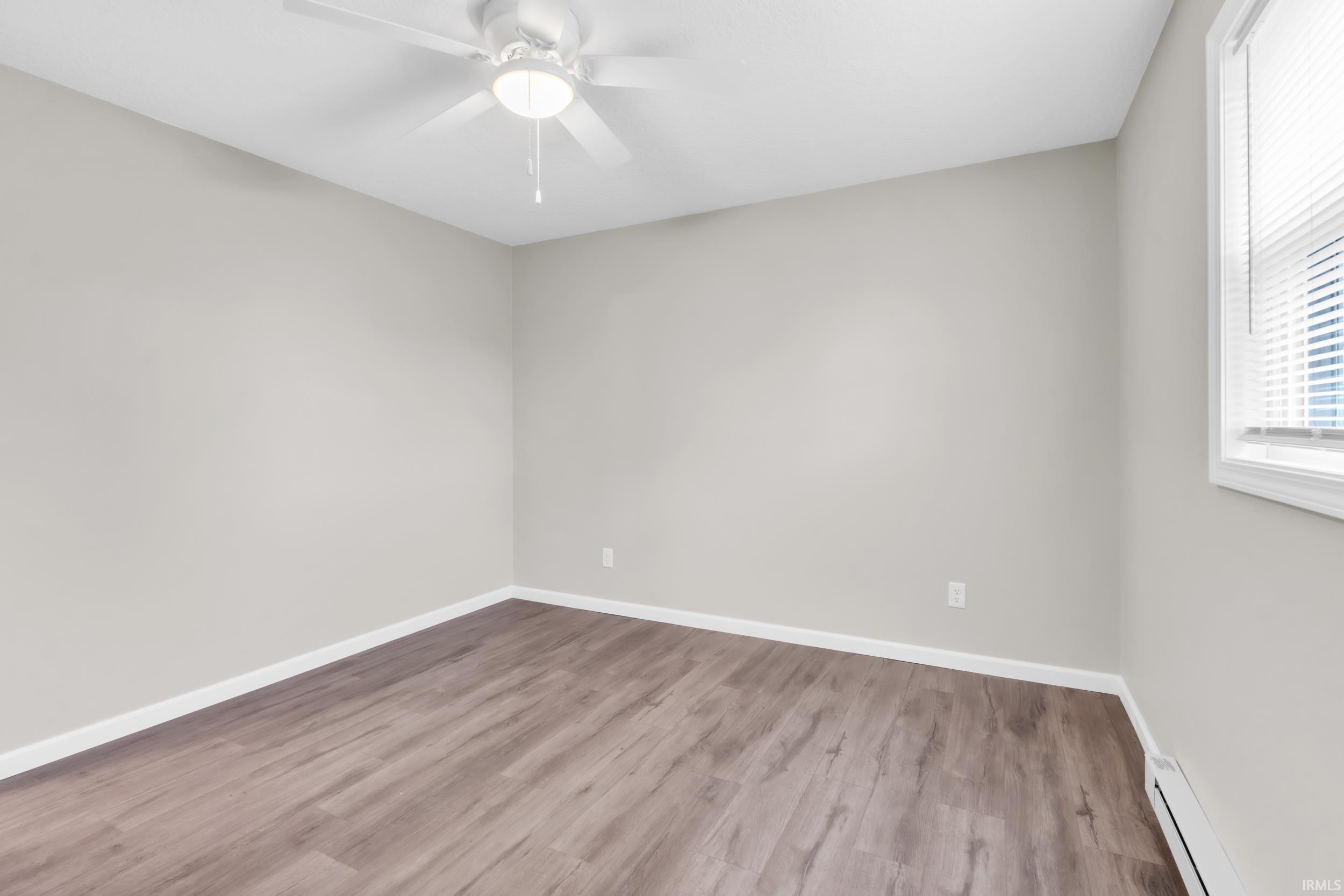 Room featuring wood-finish flooring, light gray wall paint, and white trim