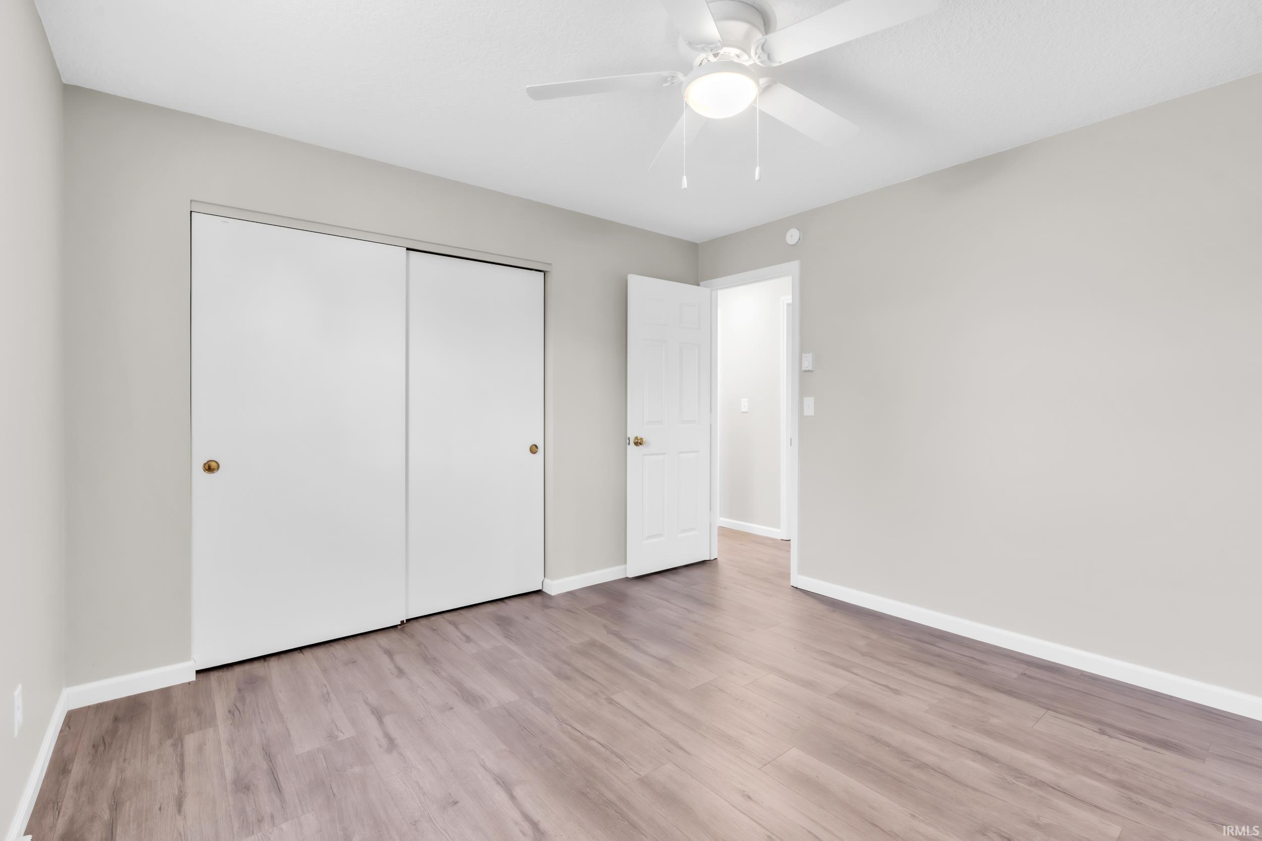 Room featuring wood-finish flooring, light grey painted walls, and white baseboards
