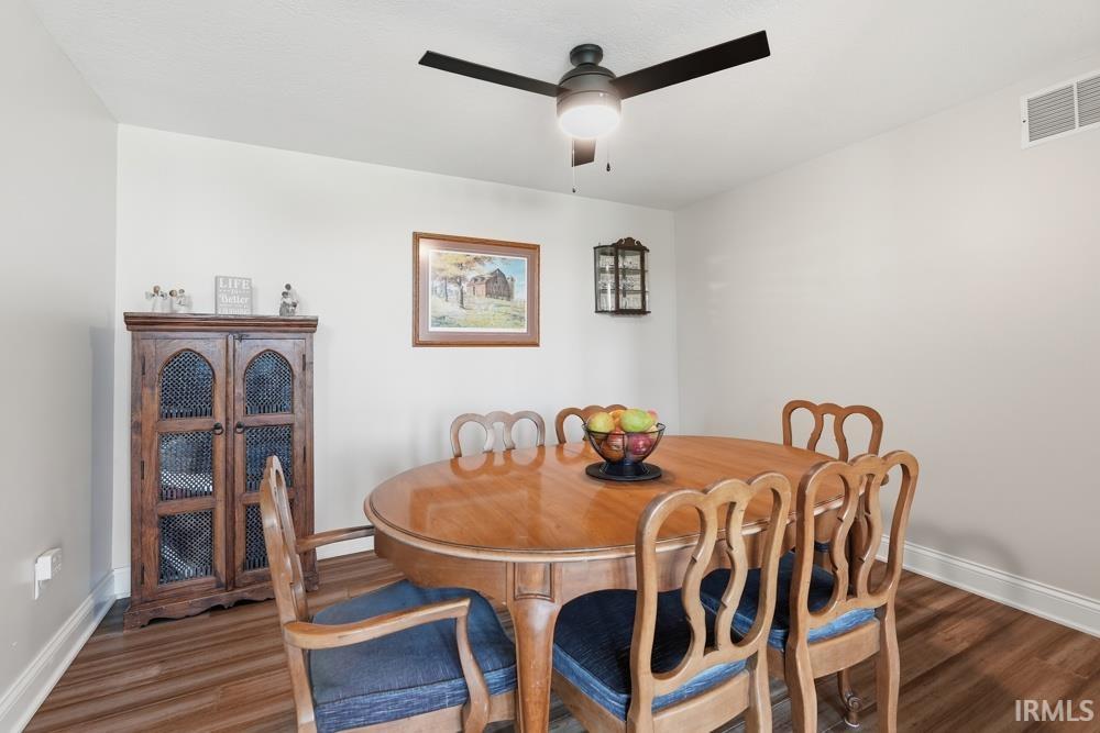 Bright dining area featuring wood-finish flooring, white baseboards, and a ceiling fan with integrated lighting