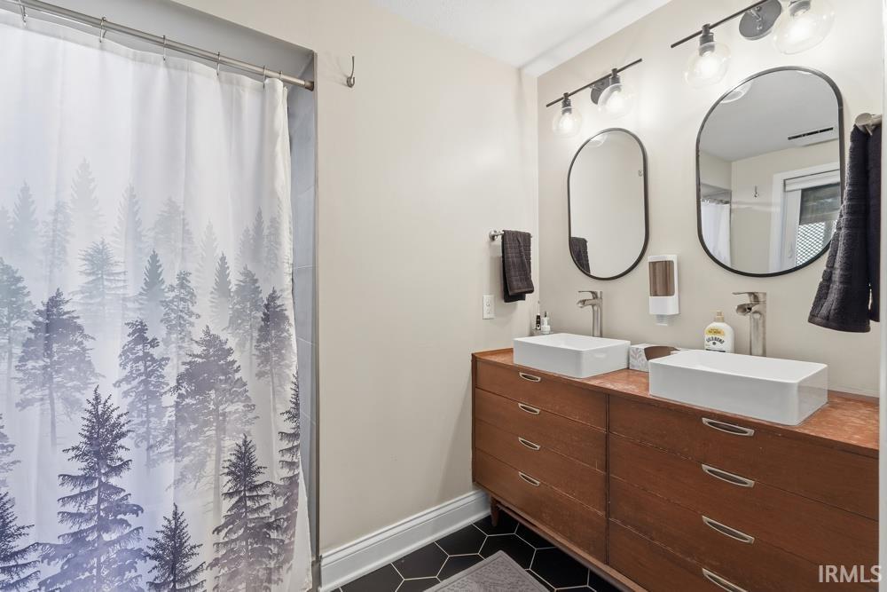 Dual vessel sinks with modern chrome faucets, complemented by a wood-finish double vanity featuring multiple drawers