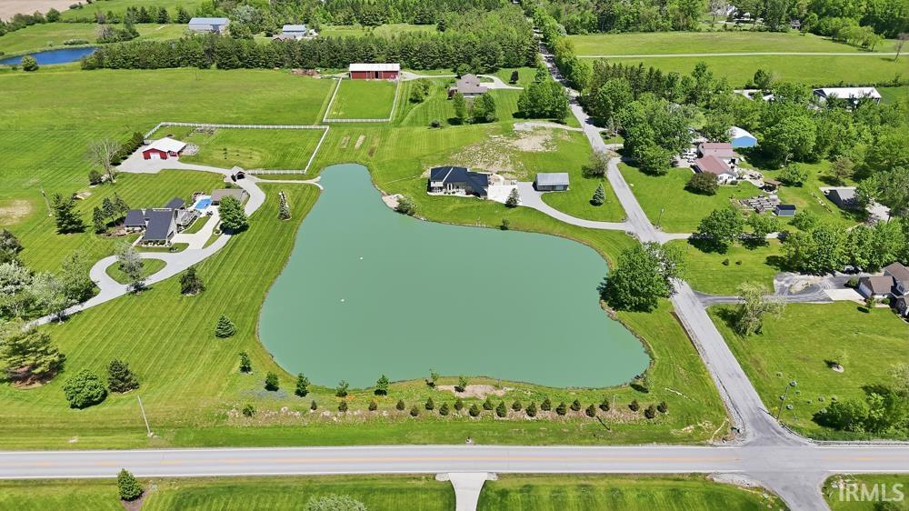 Expansive property featuring a private lake, manicured green lawns, and mature trees