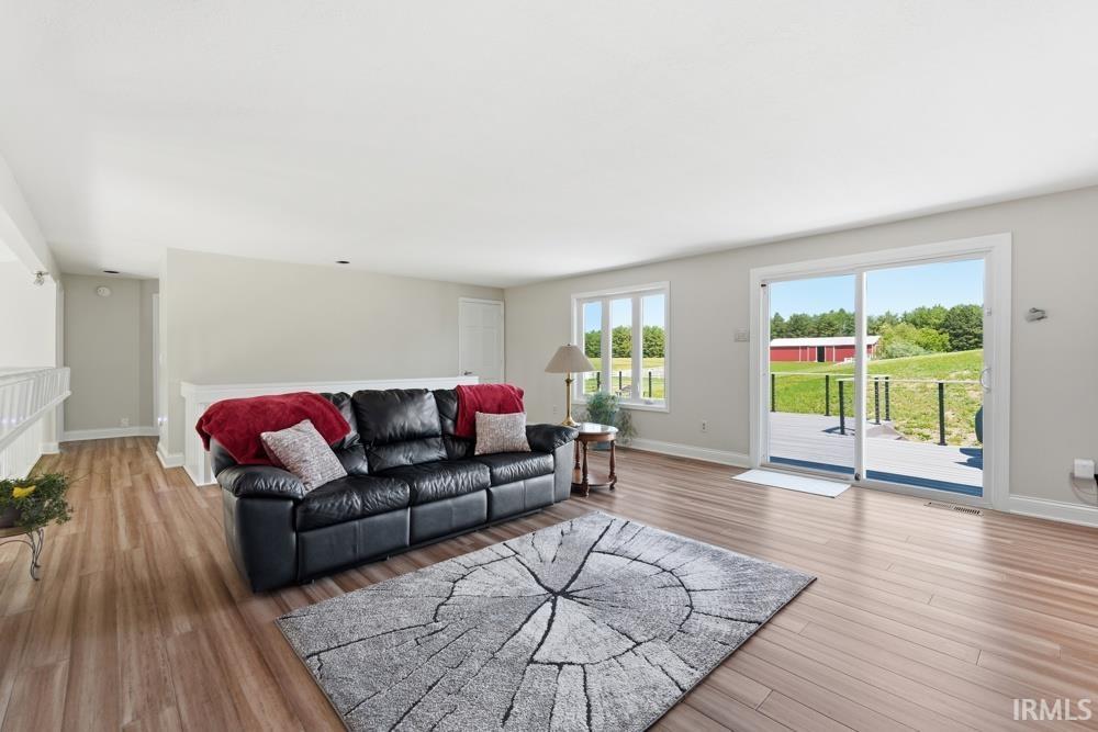 Bright living area featuring wood-finish flooring, light neutral wall colors, and a sliding glass door providing exterior access