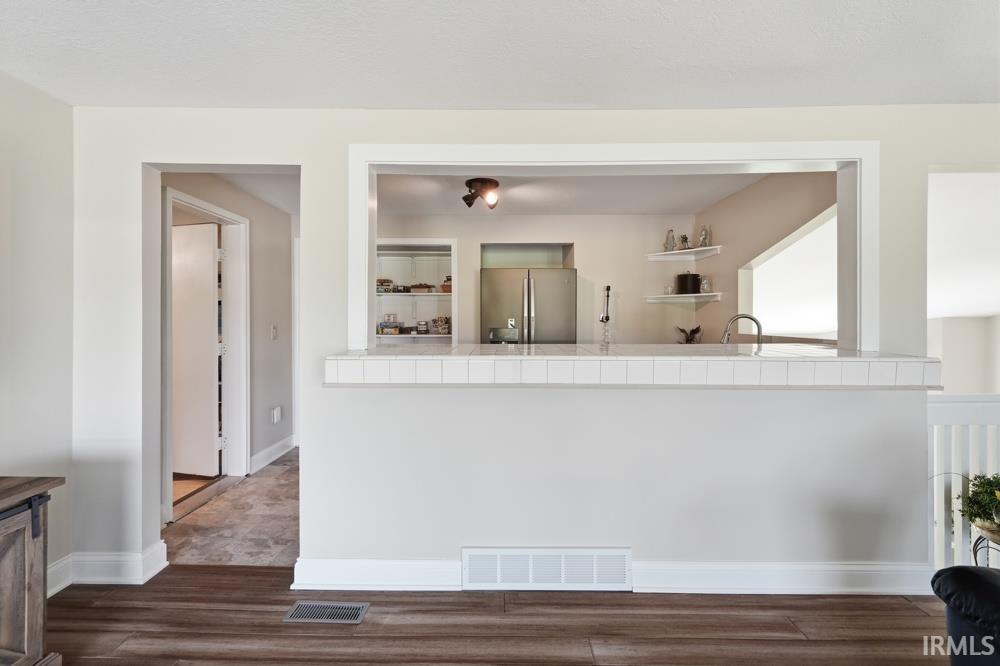 Kitchen pass-through with tile-edged countertop and stainless steel appliances