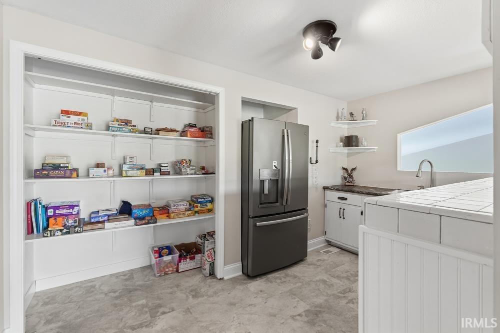 Built-in shelving storage with a contemporary refrigerator, corner floating shelves, and a single-basin sink
