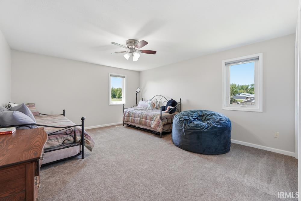 Spacious room featuring neutral wall paint, light gray carpet, and a ceiling fan with light fixture