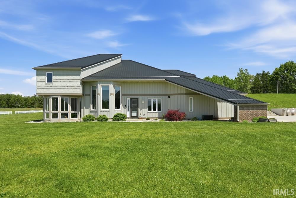 Modern architectural residence featuring a dark metal roof and light-toned siding