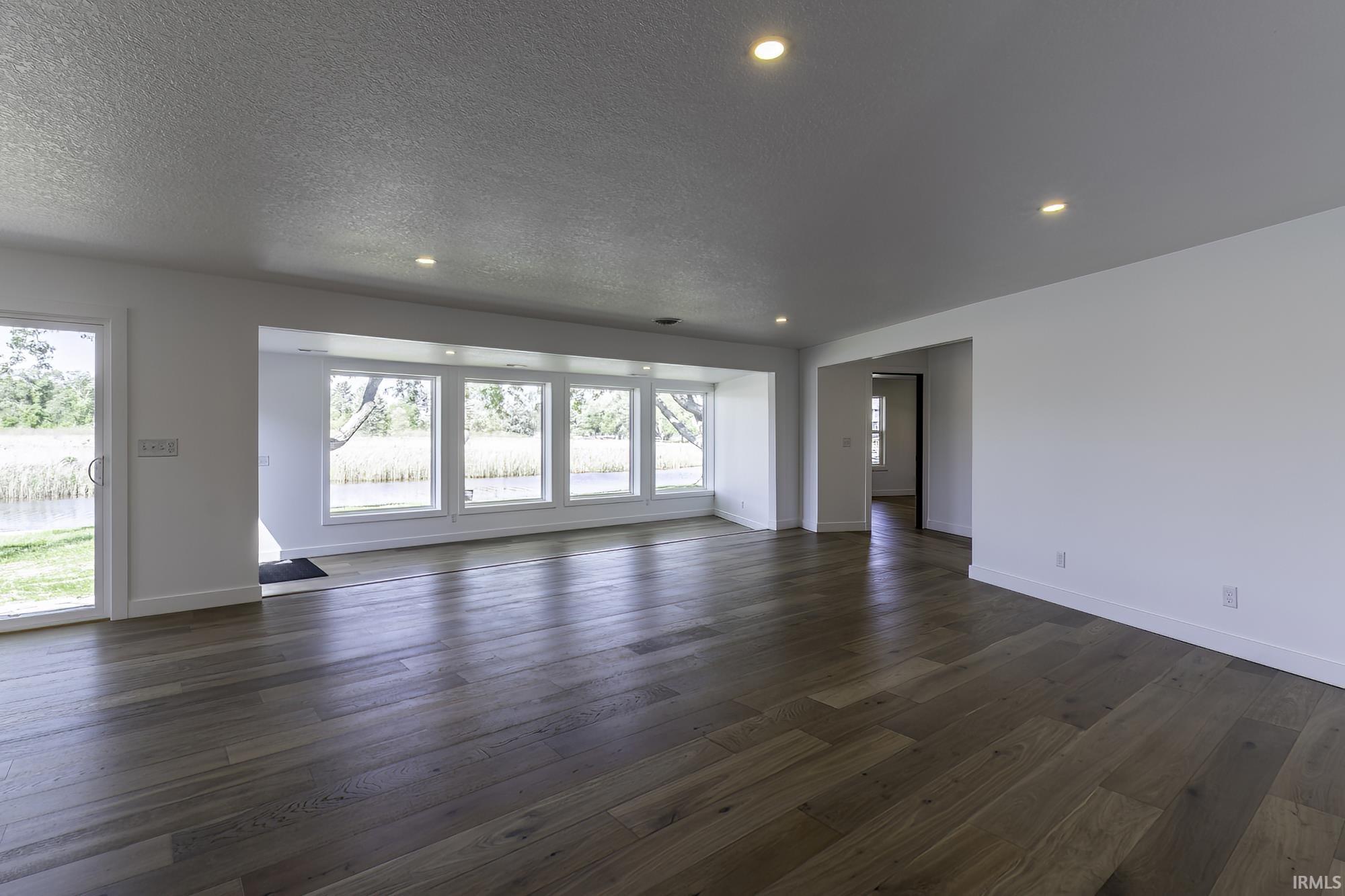Spacious interior featuring wood-finish flooring, white walls, and recessed ceiling lighting