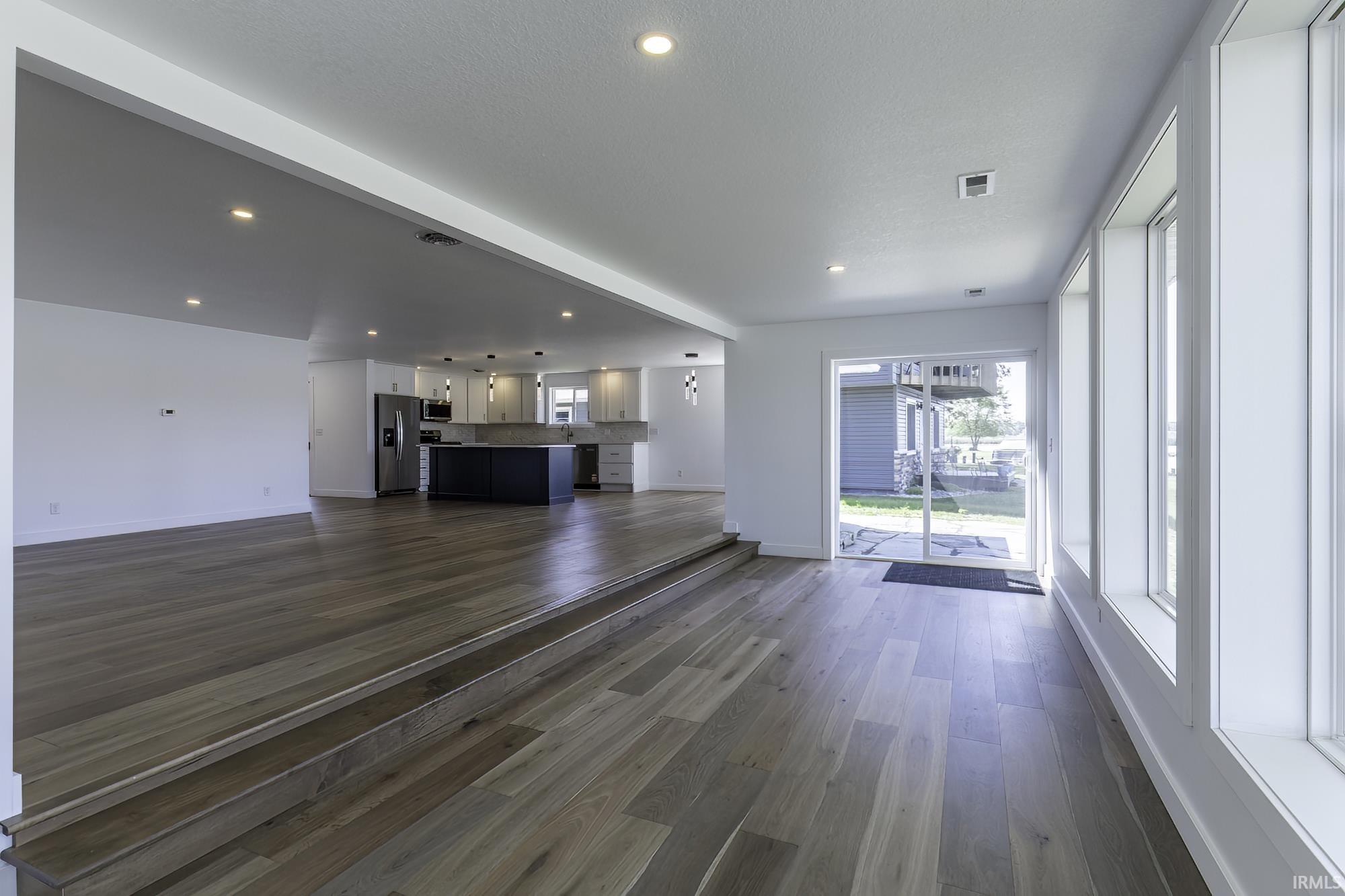 Open-concept interior featuring wood-finish flooring, recessed lighting, and a stepped floor plan