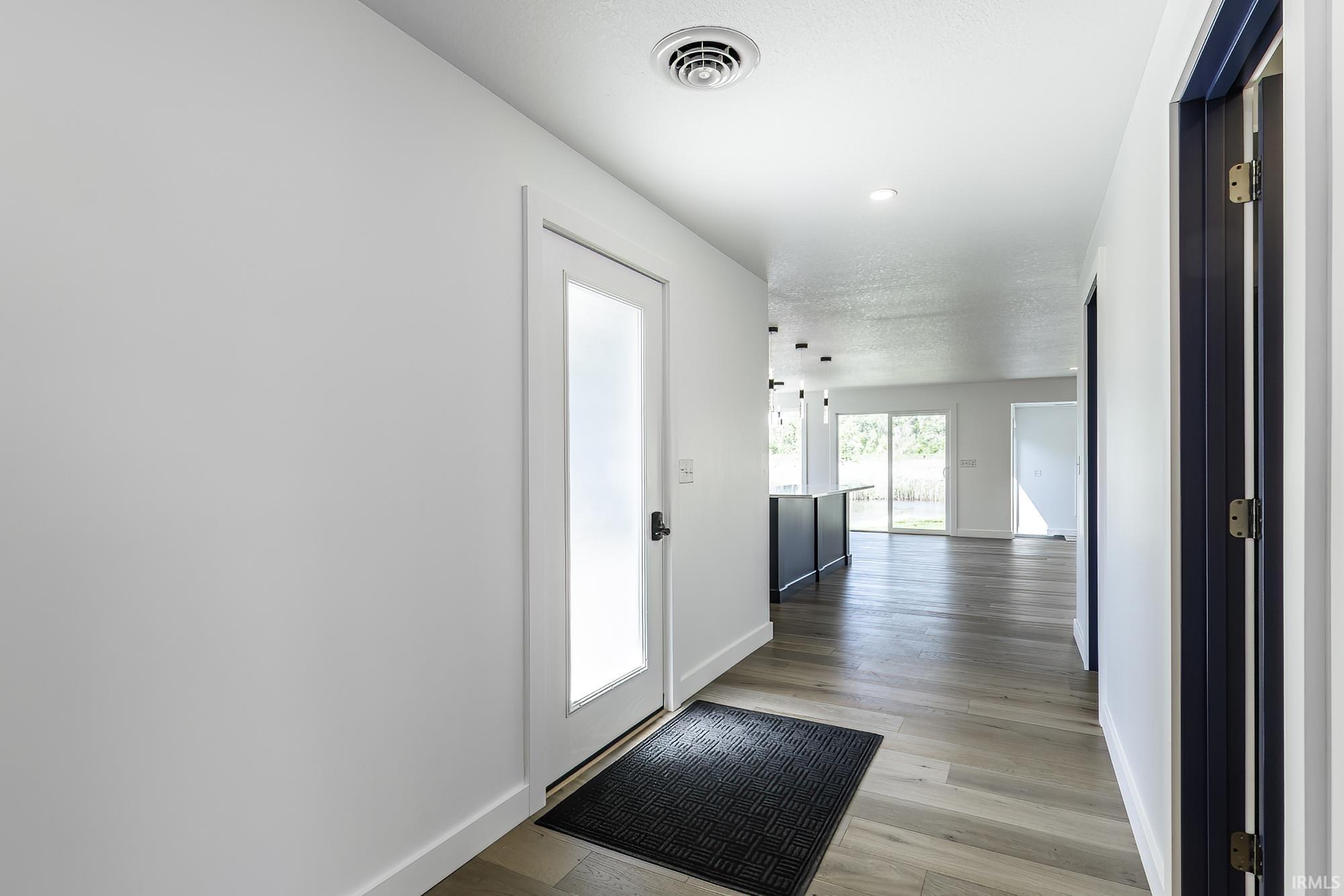 Entryway with wood-finish flooring, white walls, and a frosted glass panel door