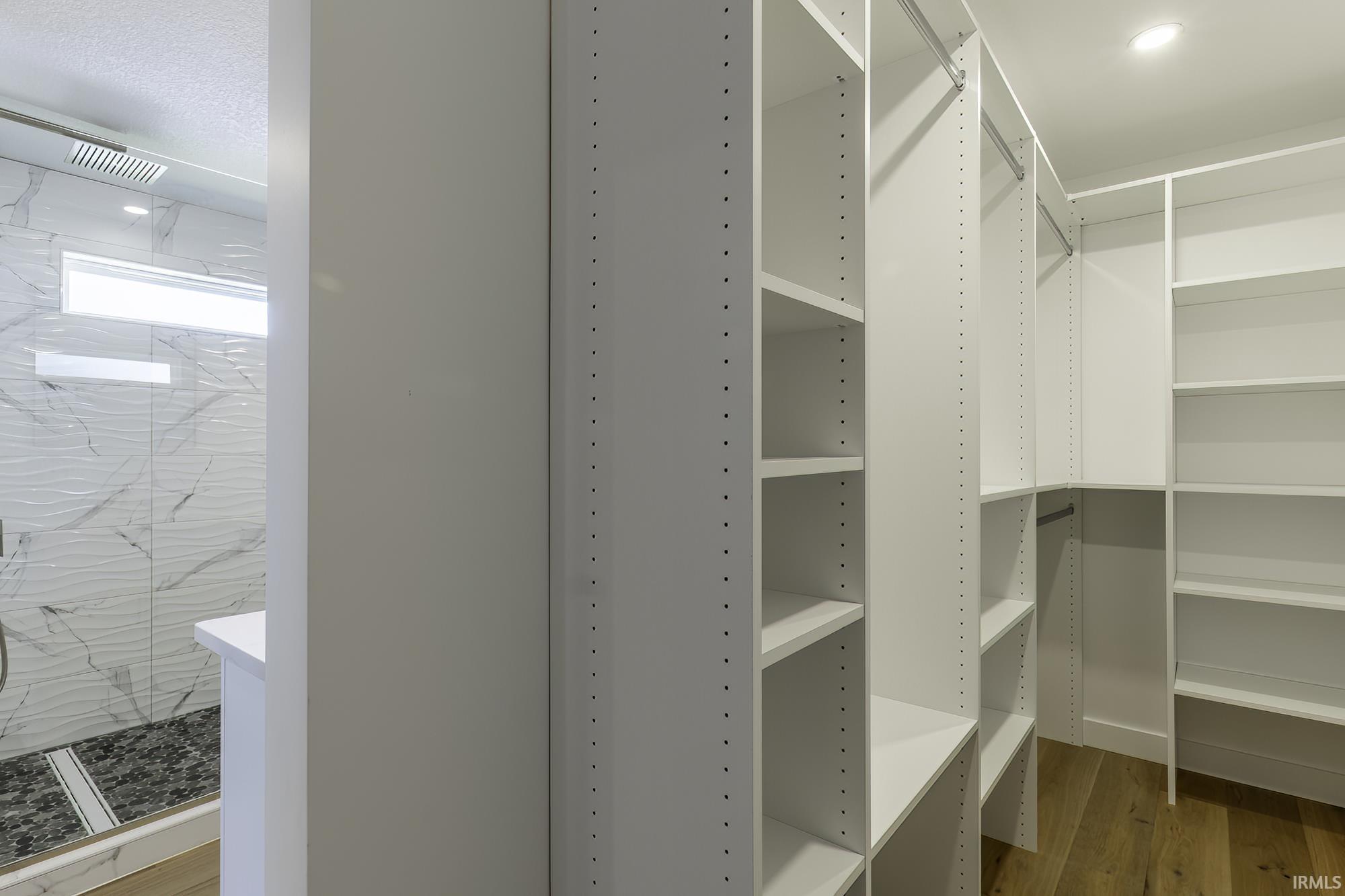 Walk-in closet featuring extensive white shelving and hanging rods