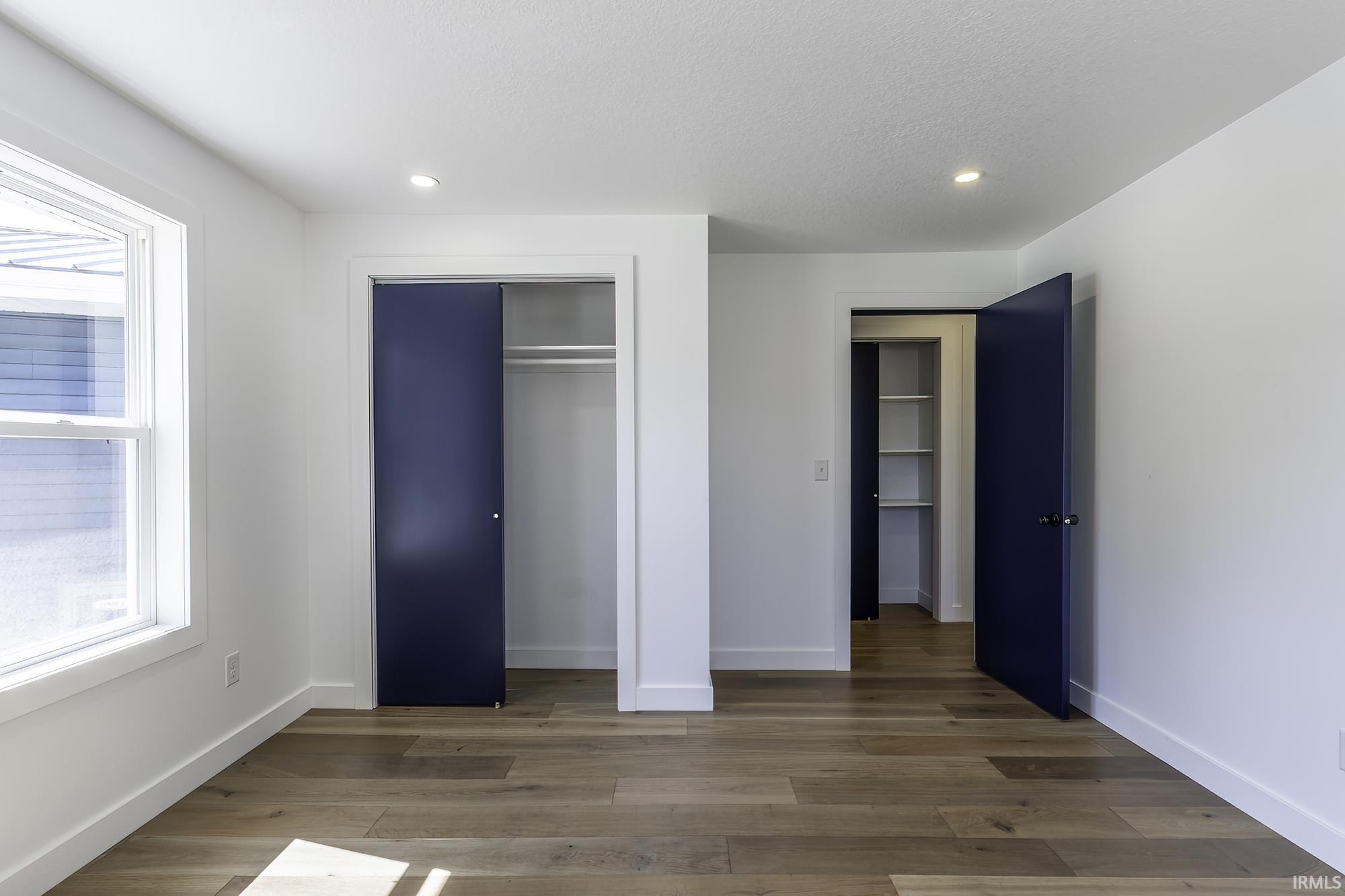 Room featuring wood-finish flooring, white walls with white trim, and recessed lighting