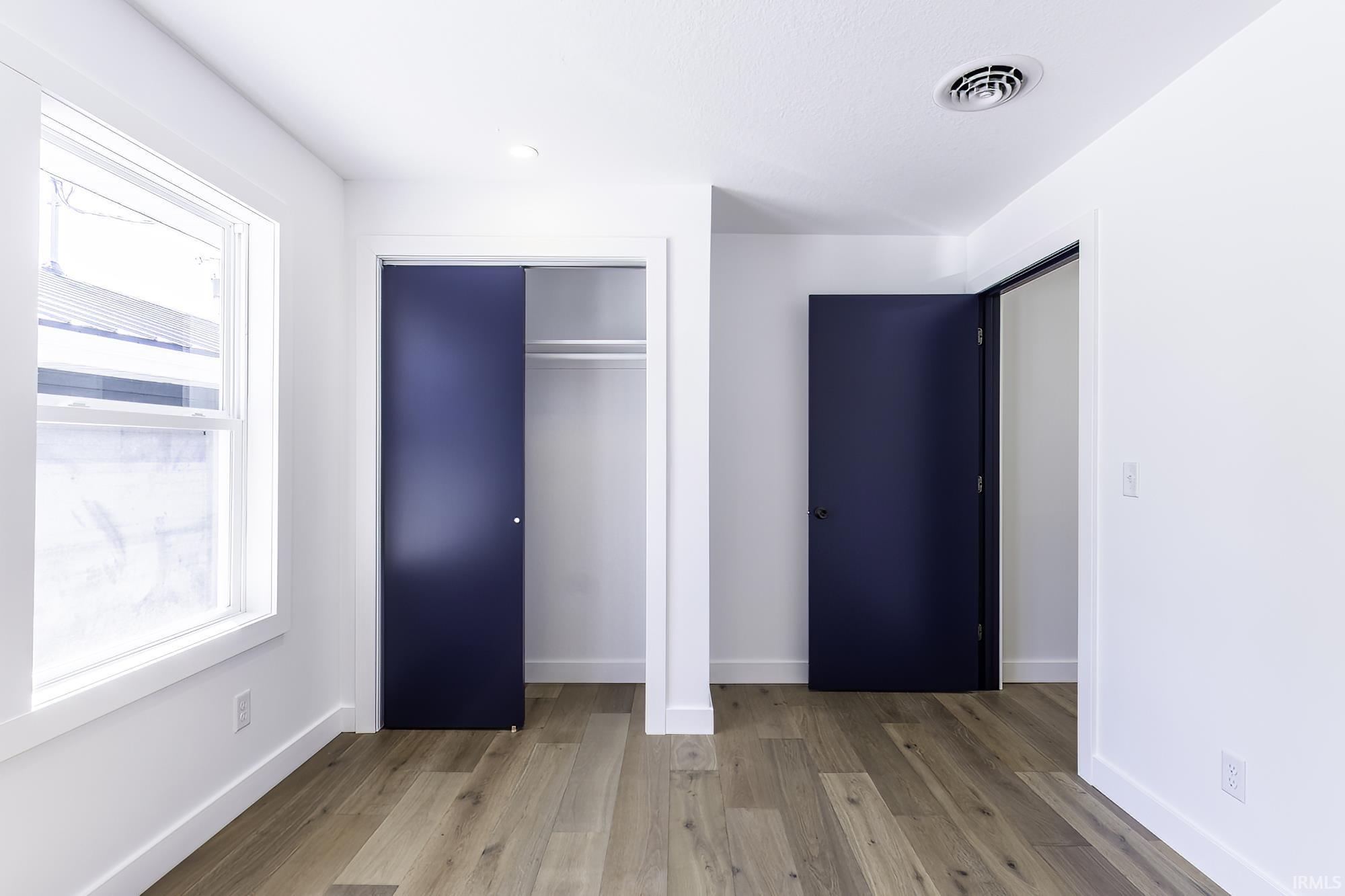 Room featuring light wood-finish flooring, white walls, and a window with white trim
