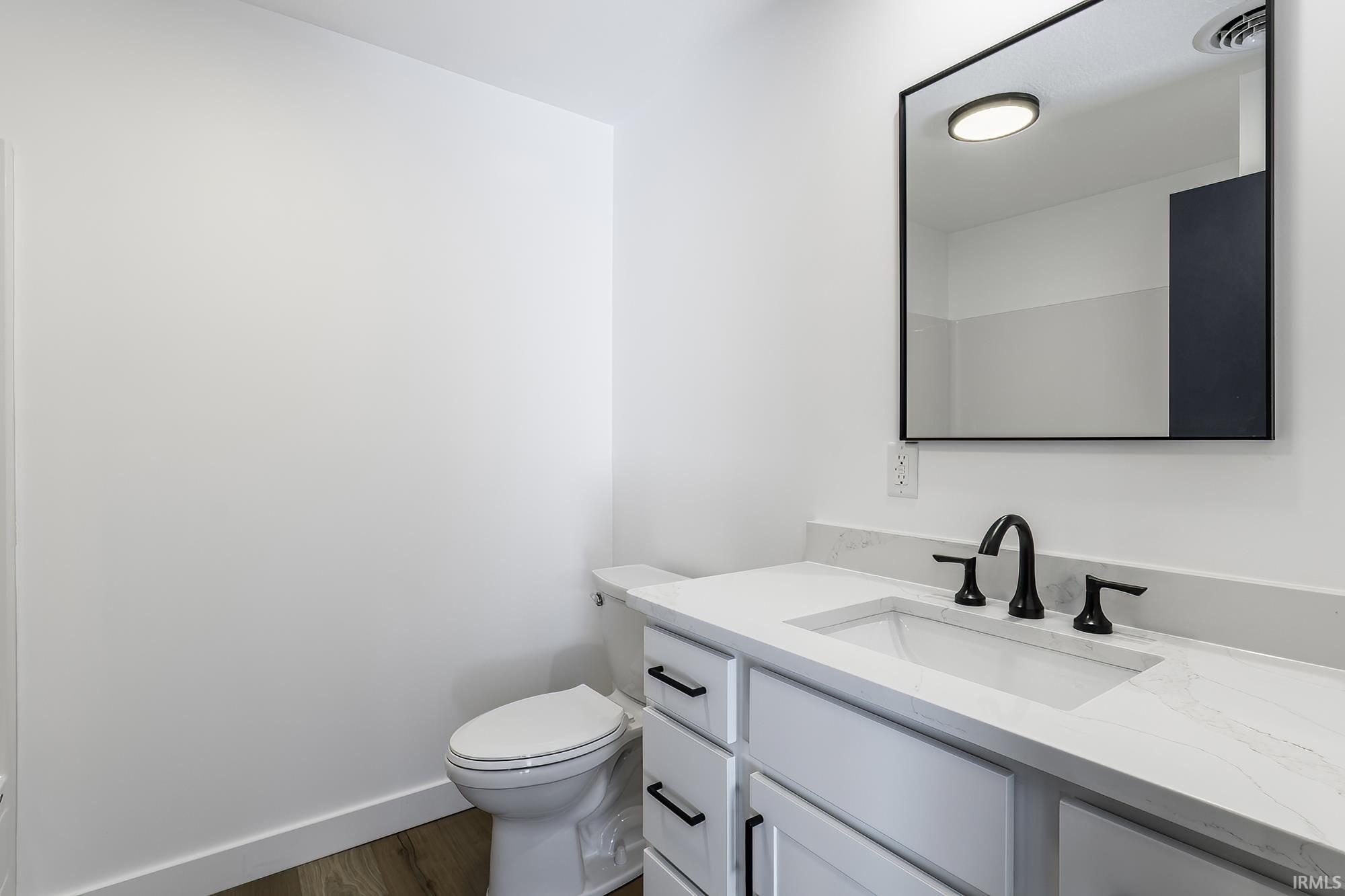 Contemporary bathroom featuring a white vanity with an integrated sink, a light-toned countertop, and matte black hardware