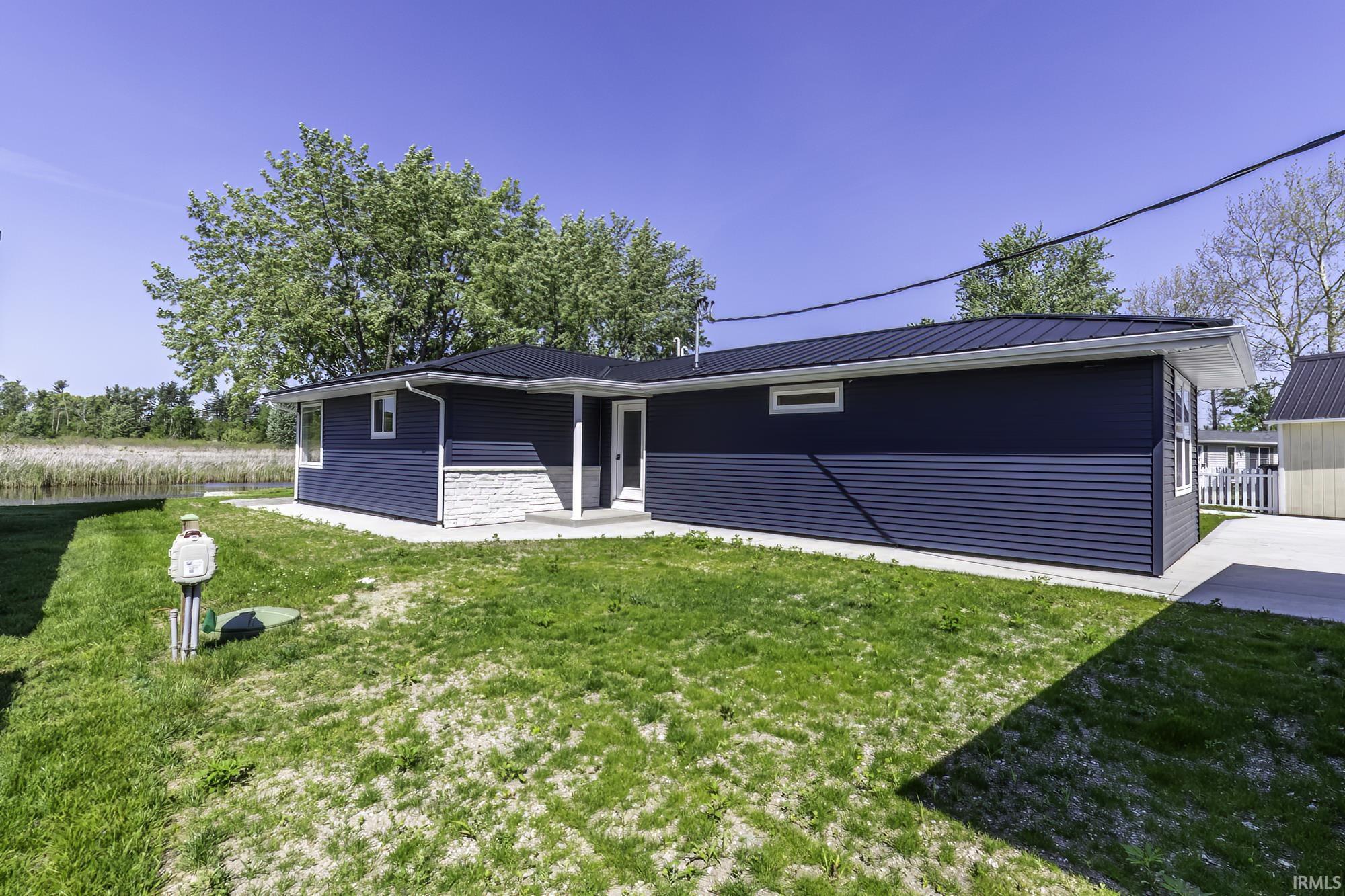Contemporary exterior featuring dark blue horizontal siding, white stone veneer accents, a dark metal roof, and white trim
