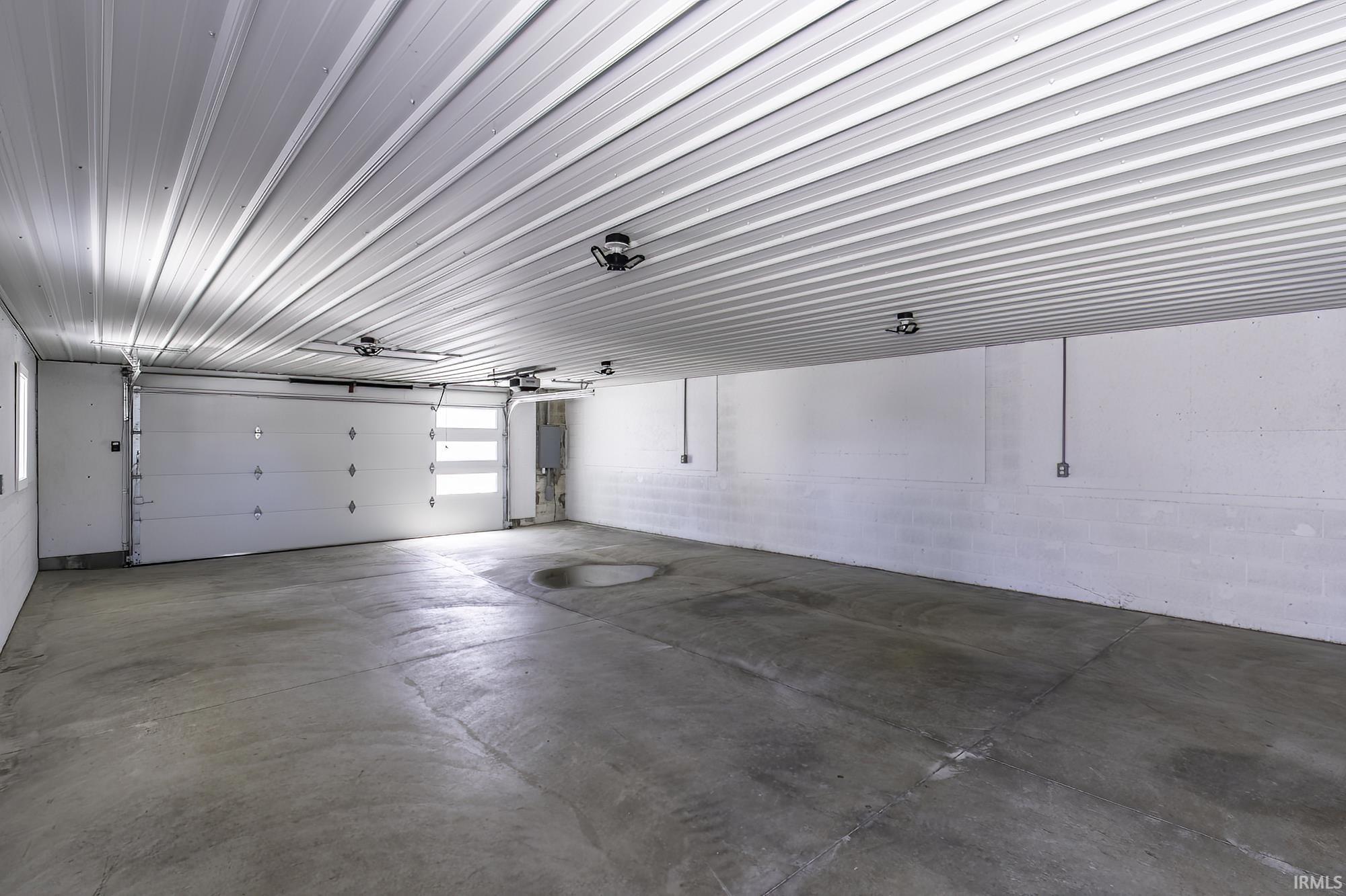 Spacious garage featuring a concrete floor, corrugated metal ceiling, and white block walls