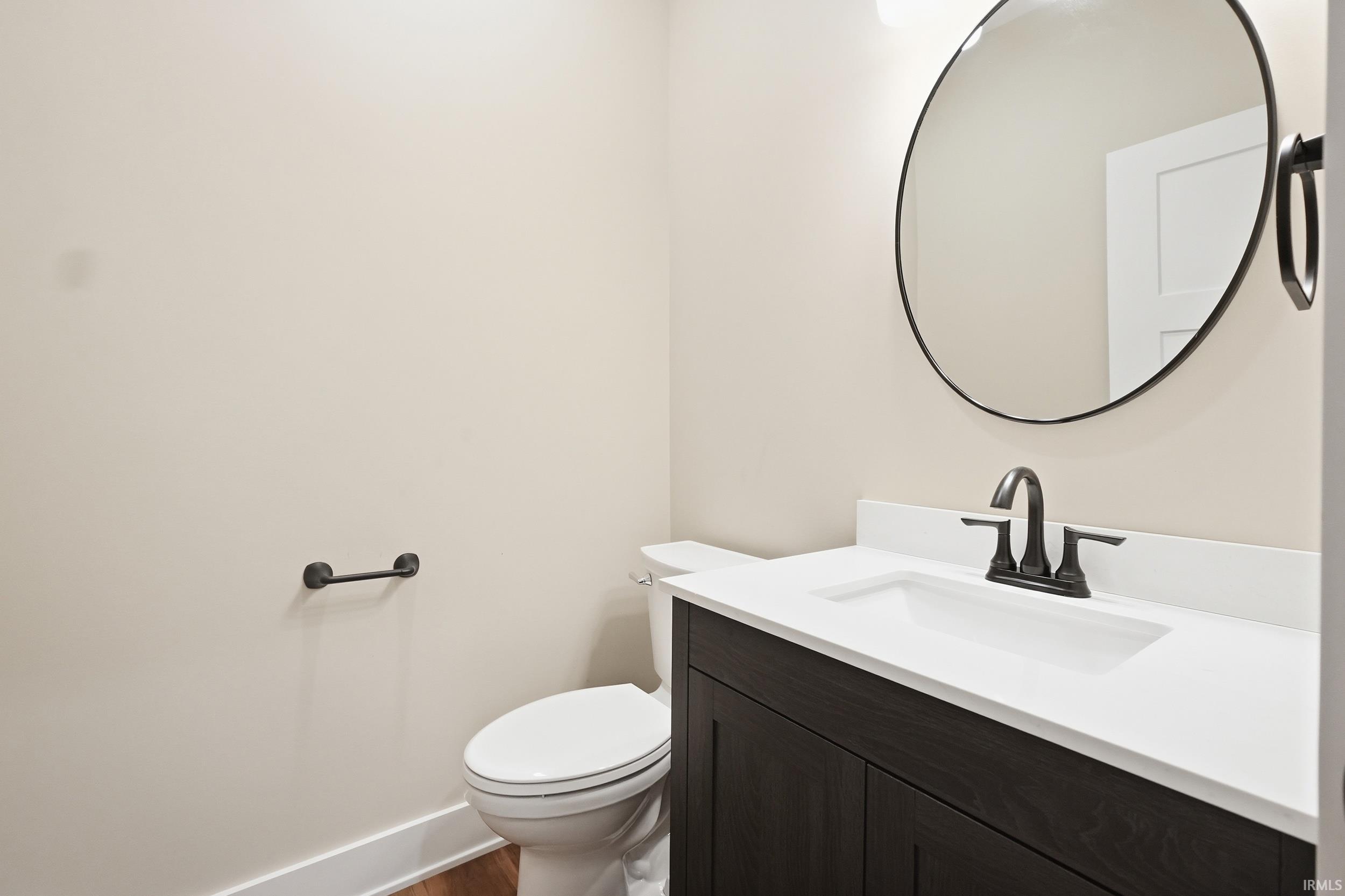 Bathroom vanity featuring a dark wood-finish cabinet, white countertop with integrated sink, and black hardware