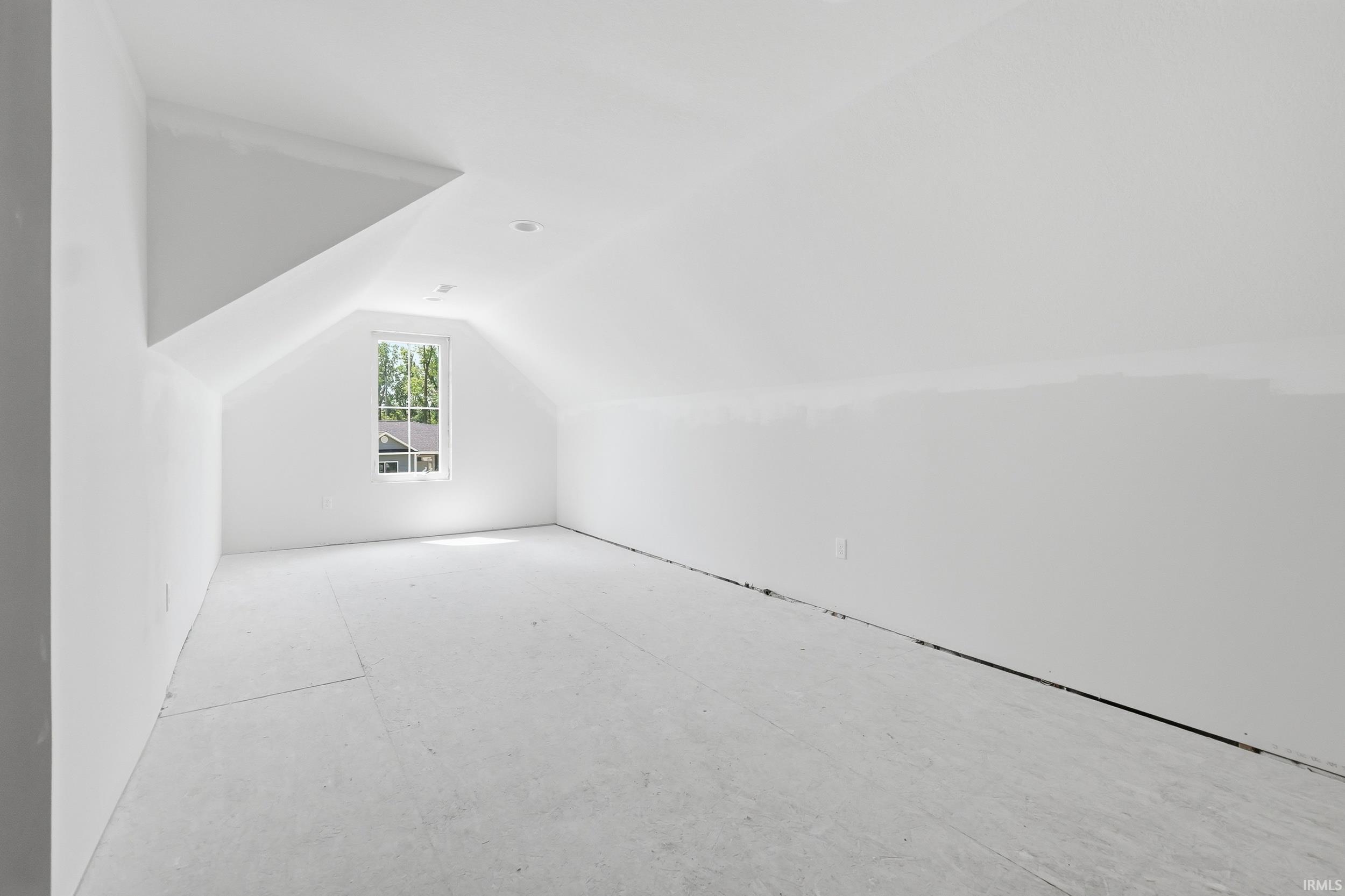 Spacious room with a vaulted ceiling, recessed lighting, and a single window