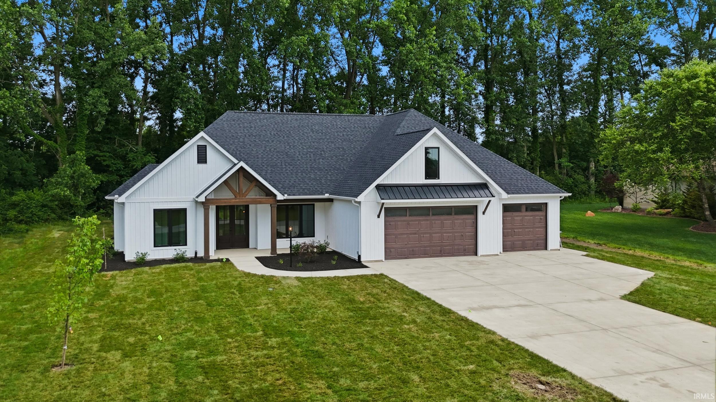 Modern farmhouse exterior featuring white board and batten siding, a dark shingle roof, a prominent wooden beam entryway, a concrete driveway, and a two-car garage with wood-finish doors