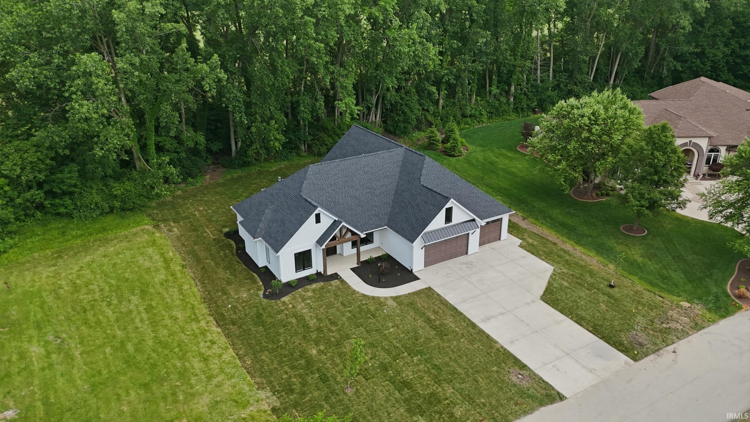 Modern farmhouse exterior with dark gray roofing, white siding, and wood-finish accents