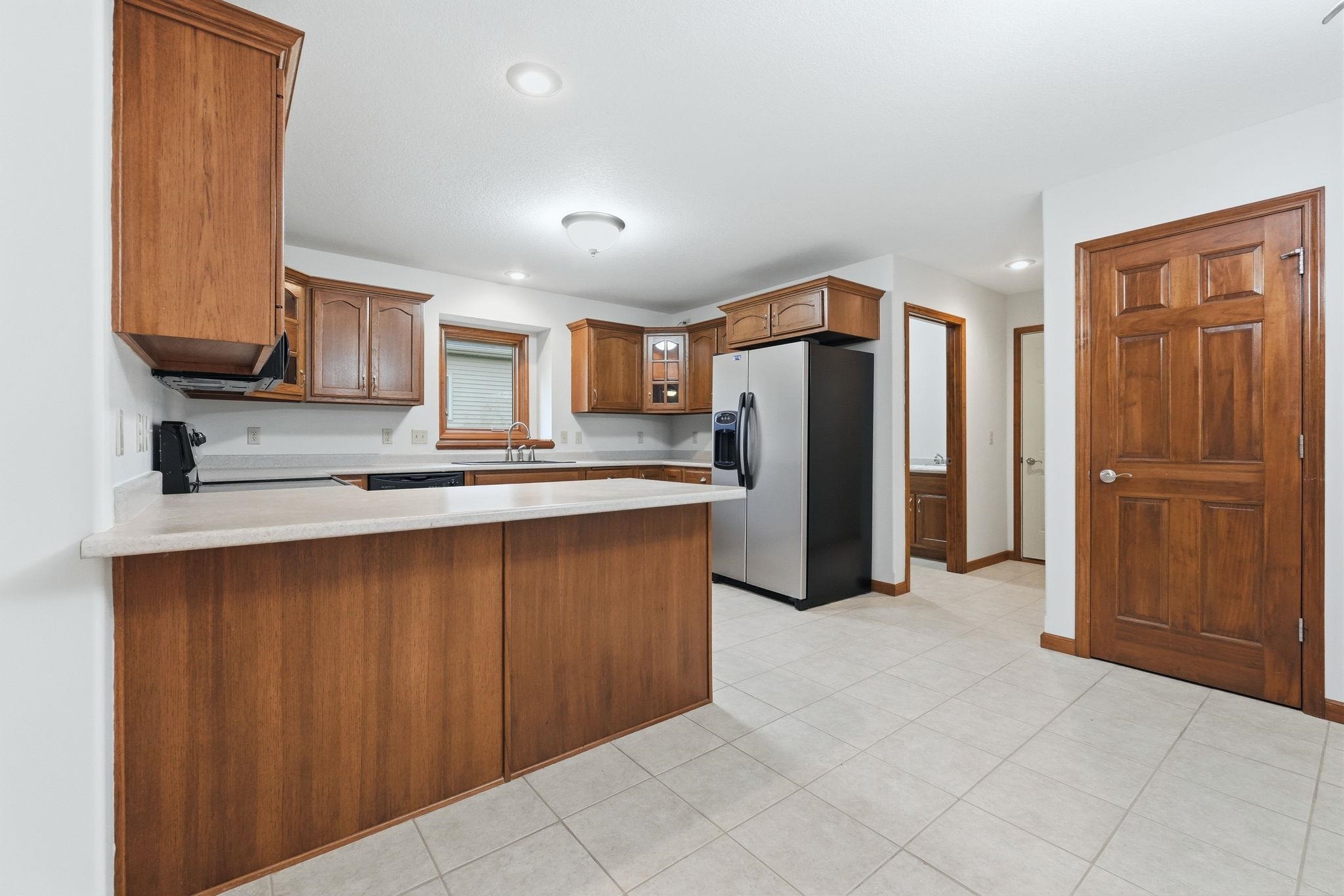 Kitchen featuring wood-finish cabinetry, light-toned countertops, and a full suite of stainless steel appliances