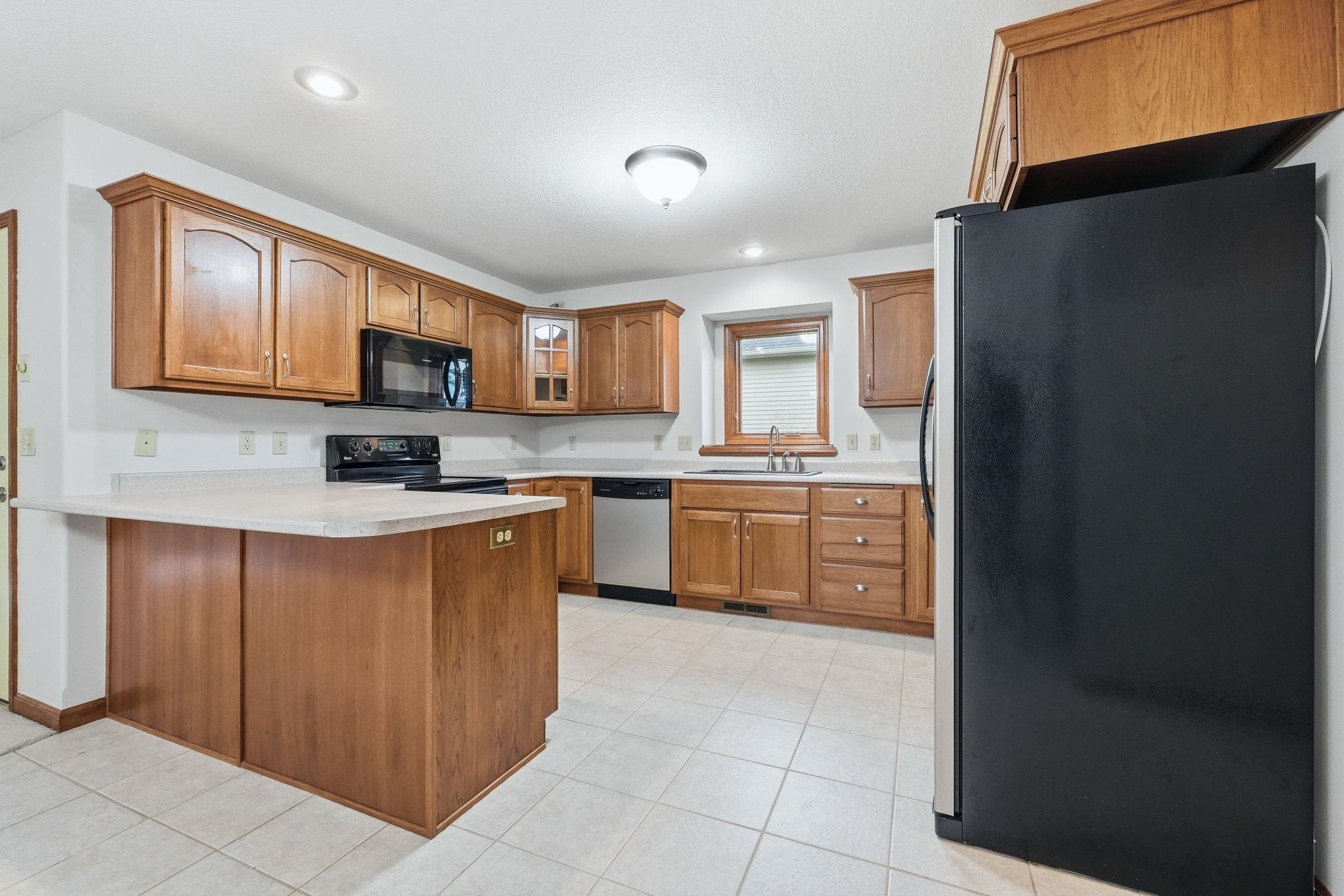 Kitchen featuring extensive wood cabinetry, light-toned countertops, and tile flooring