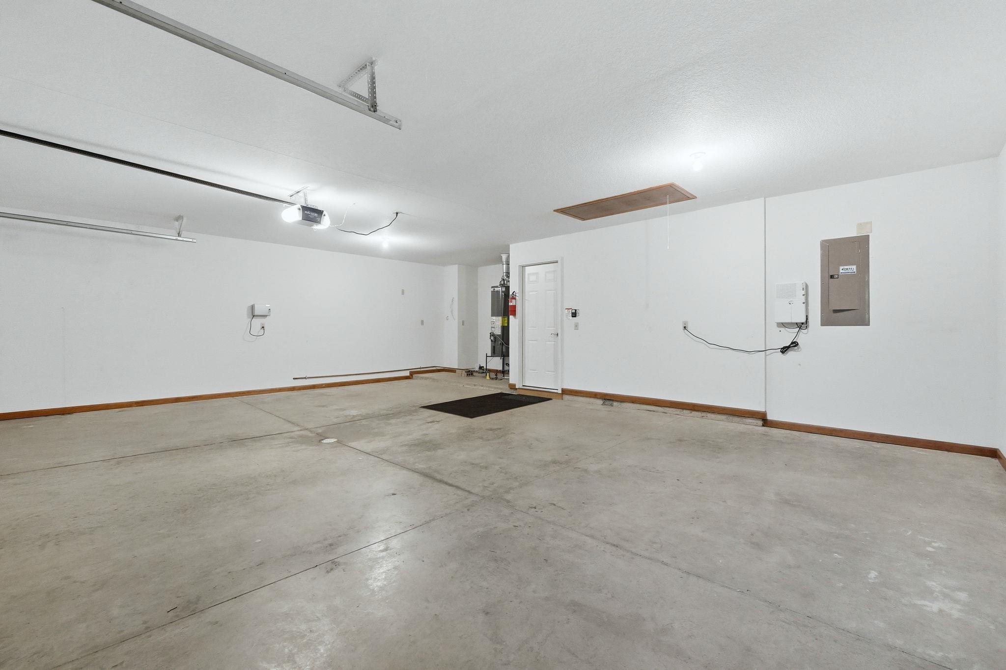 Spacious garage featuring a concrete floor, white painted walls, and wood trim