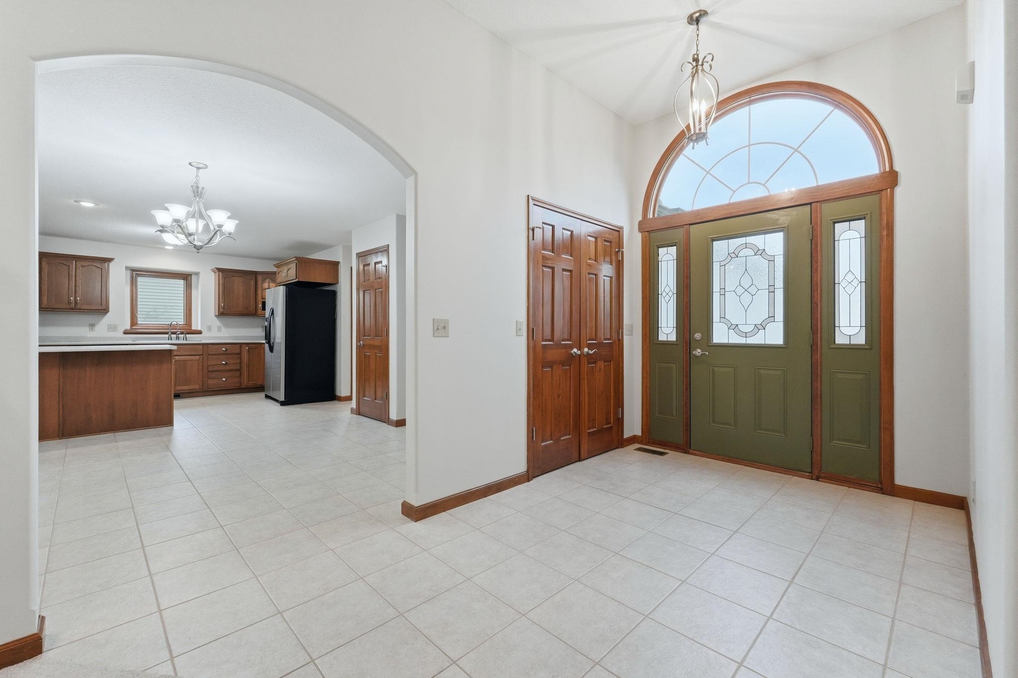 Entryway featuring a decorative arched transom window, a green front door with leaded glass inserts, and side panel windows
