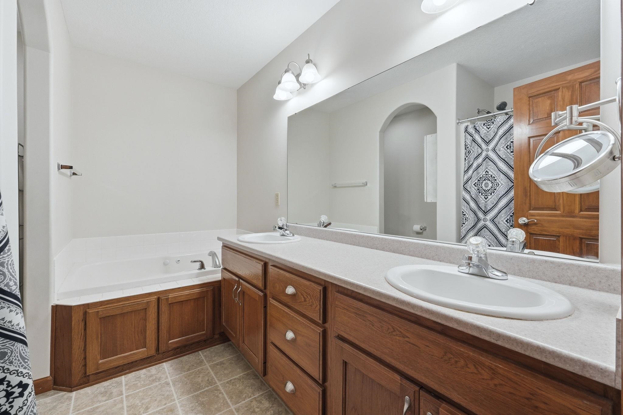 Bathroom featuring a double vanity with wood cabinetry, light-toned countertops, and dual integrated sinks