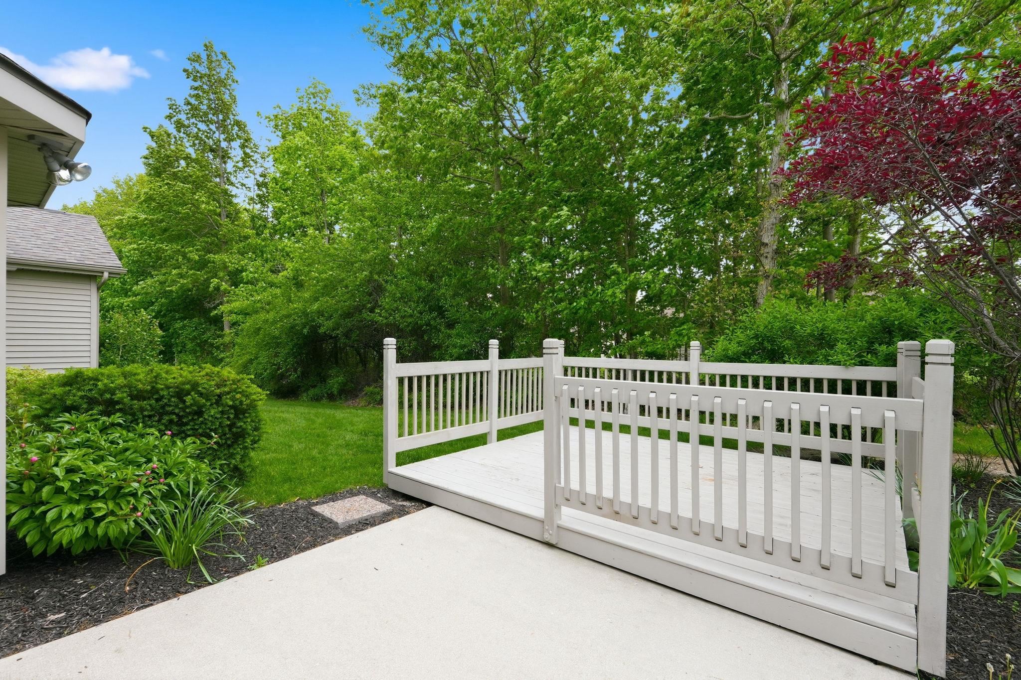 Exterior patio area with a light-colored, multi-level deck featuring a white railing