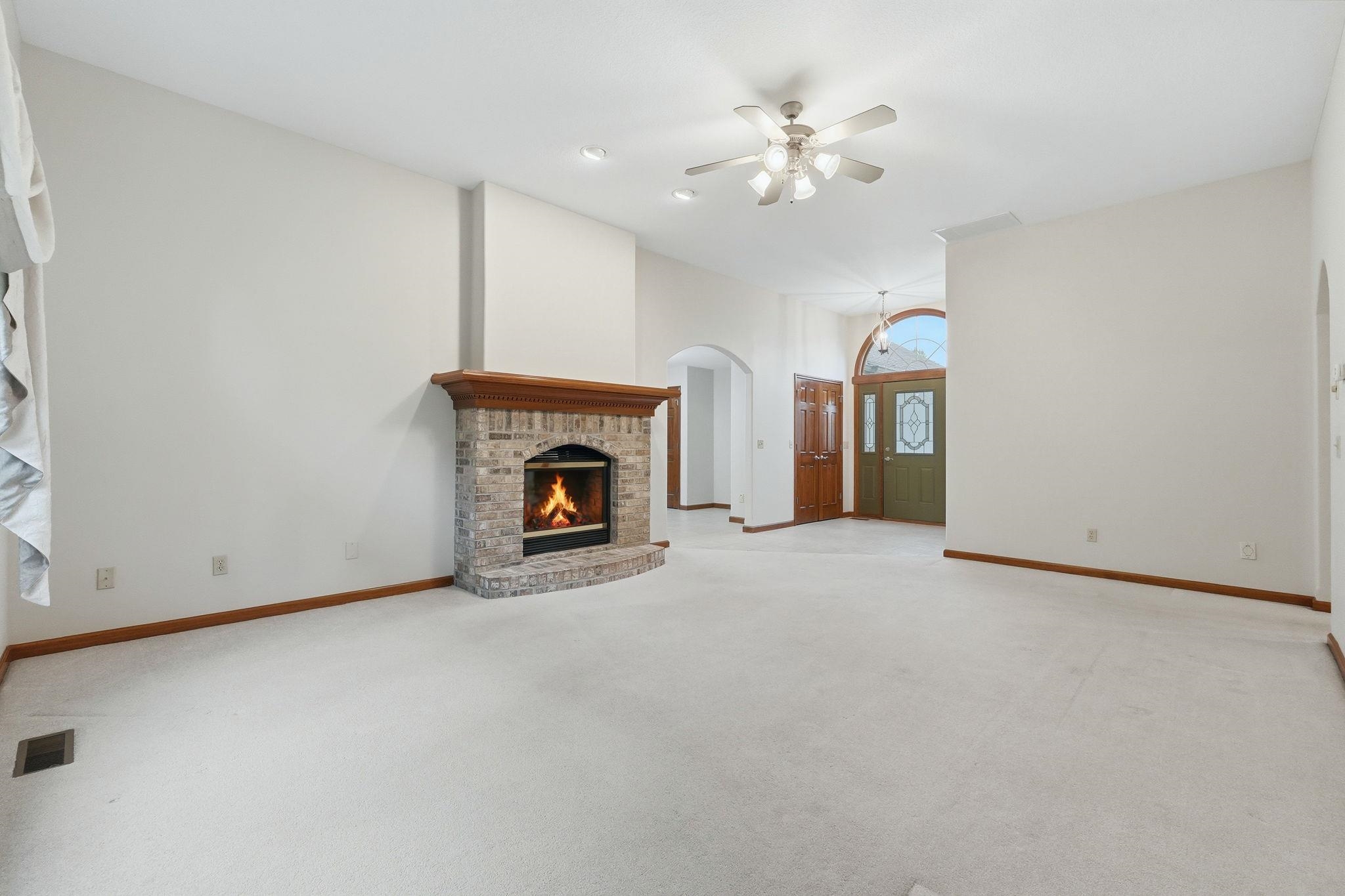 Spacious living area featuring a brick fireplace with a wood mantel