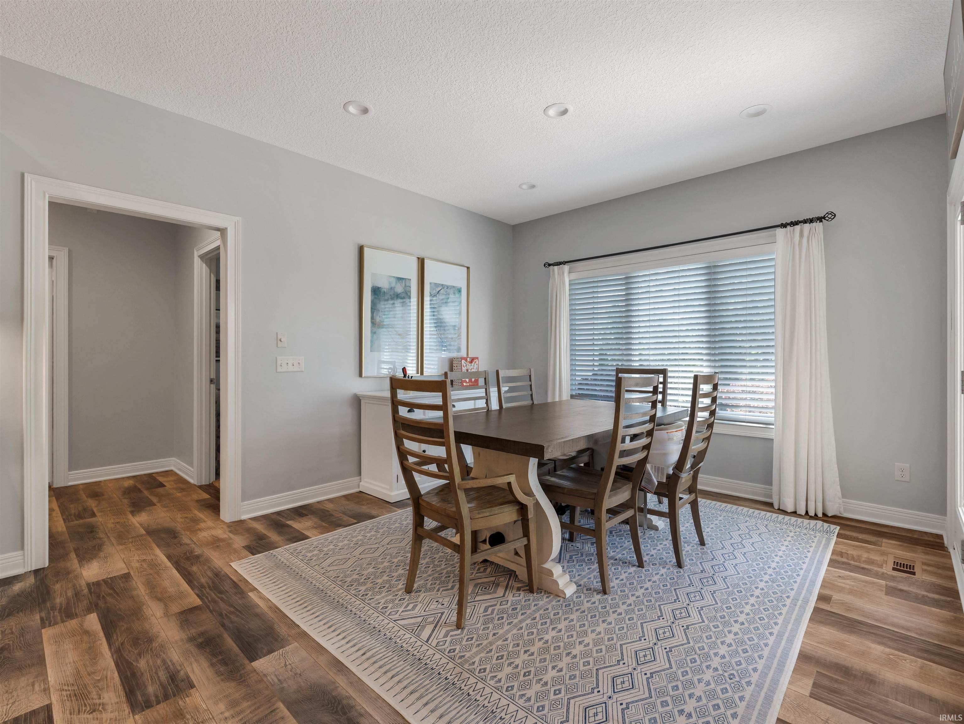 Dining area featuring wood-finish flooring, recessed lighting, and a large window with blinds
