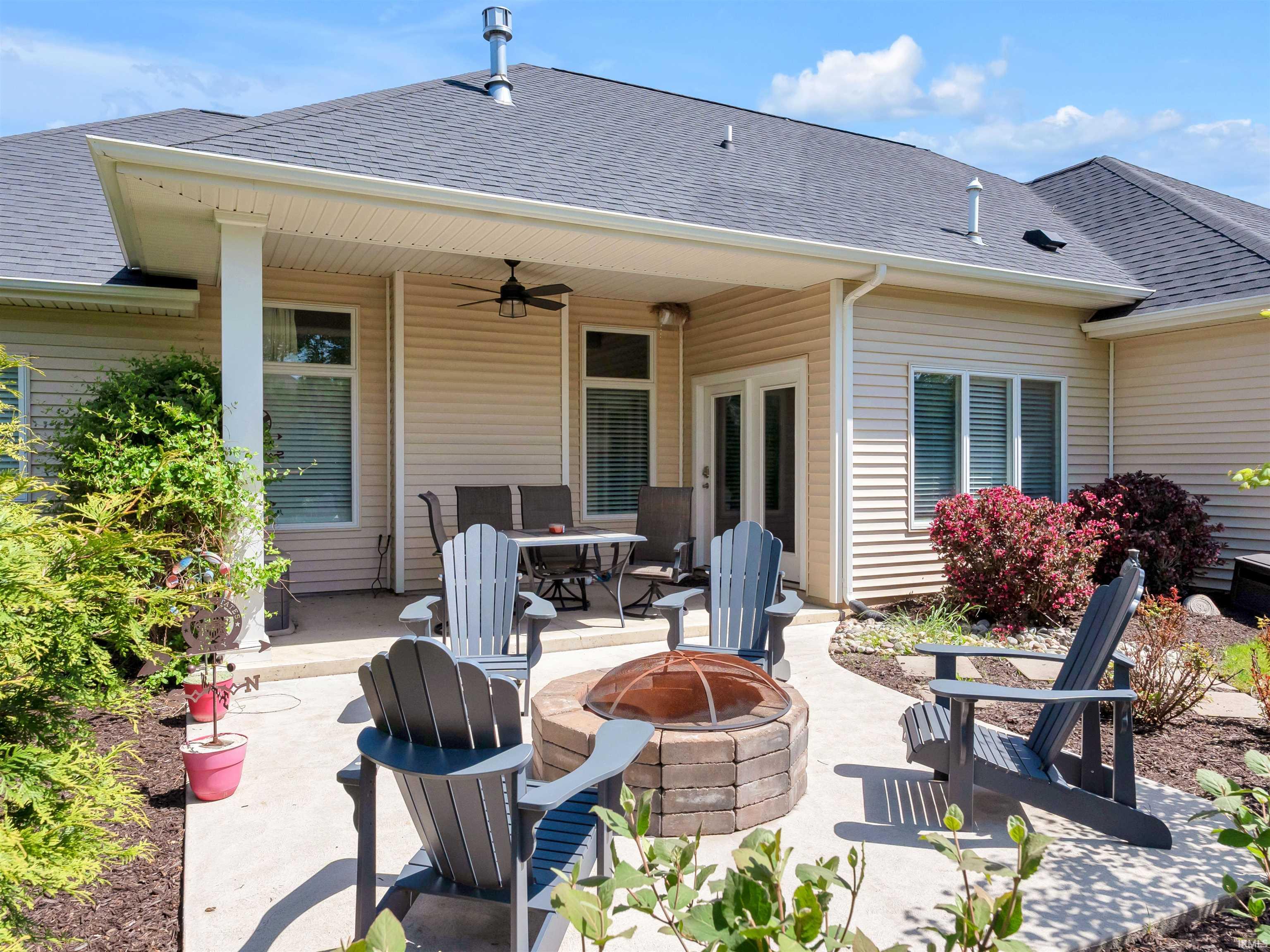 Outdoor patio featuring a built-in fire pit, covered seating area with ceiling fan, and direct access to the interior via French doors
