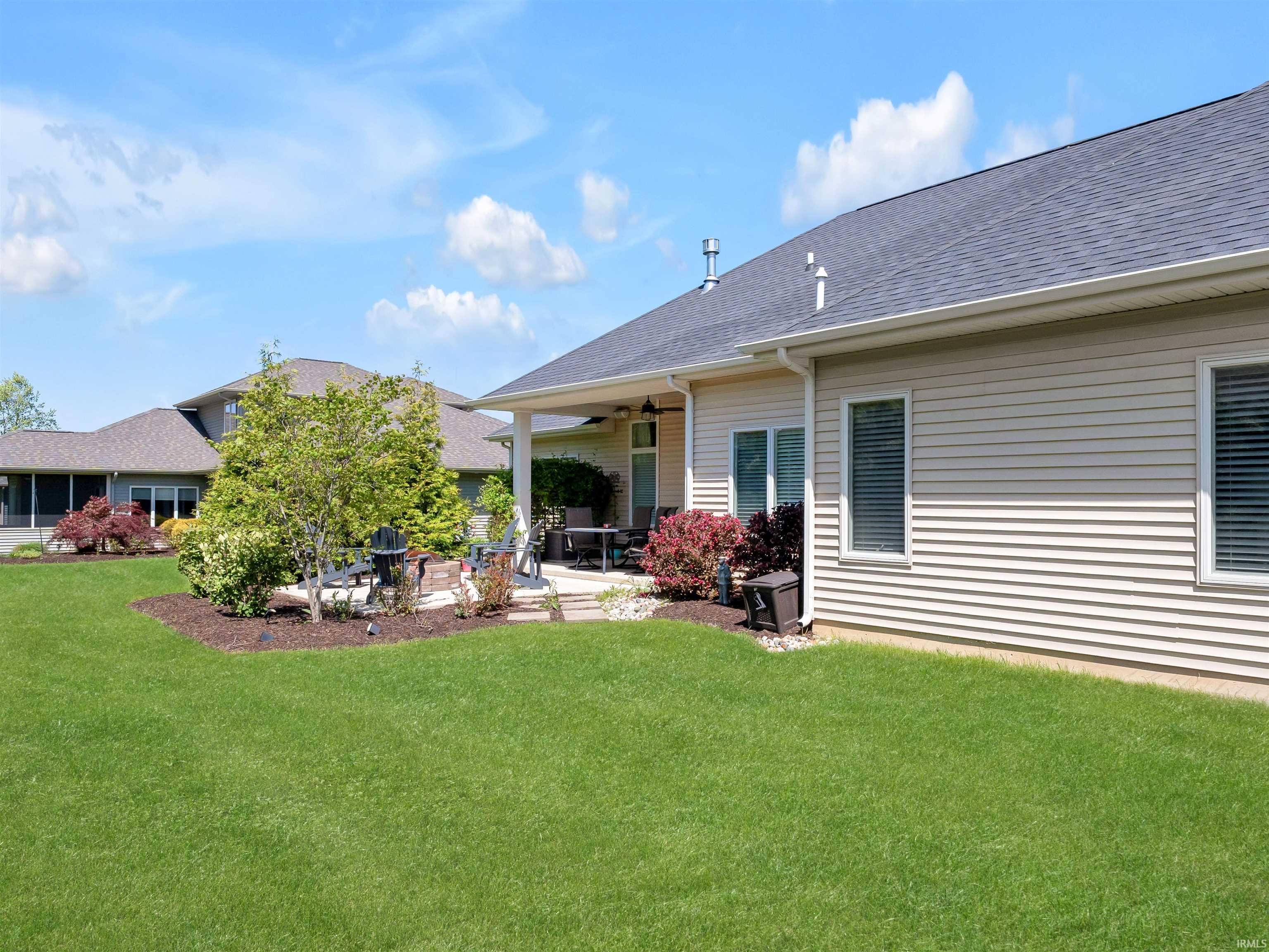 Expansive green lawn with a covered patio featuring a ceiling fan and recessed lighting