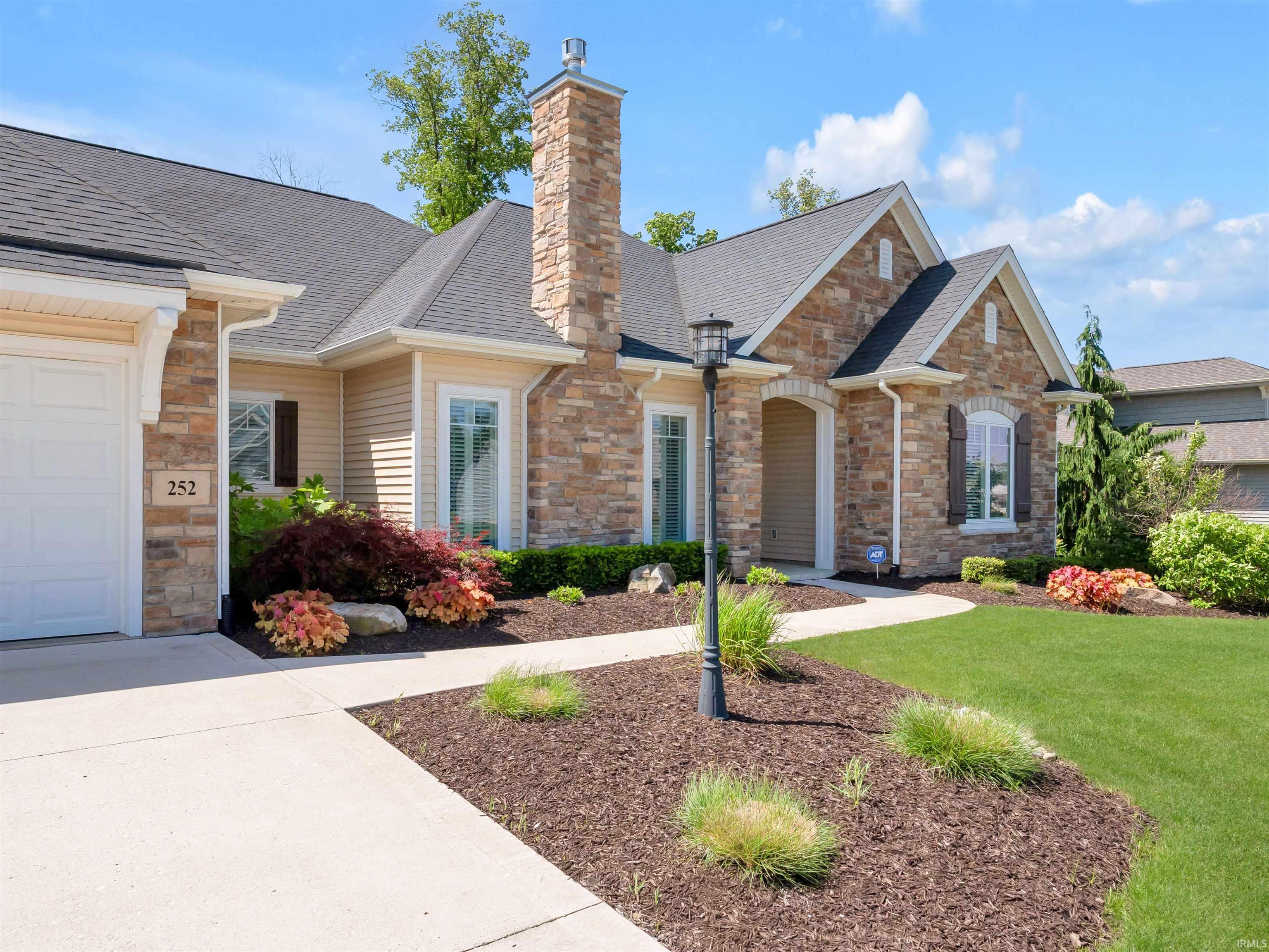 Stone and siding exterior with an attached garage, a chimney, and arched entryways