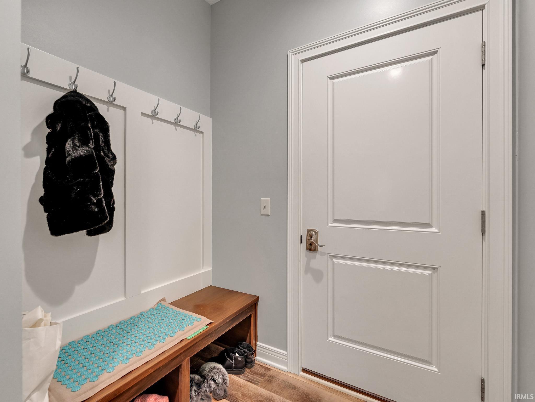 Entryway with wood-finish flooring, a solid panel interior door, and a built-in bench with open storage
