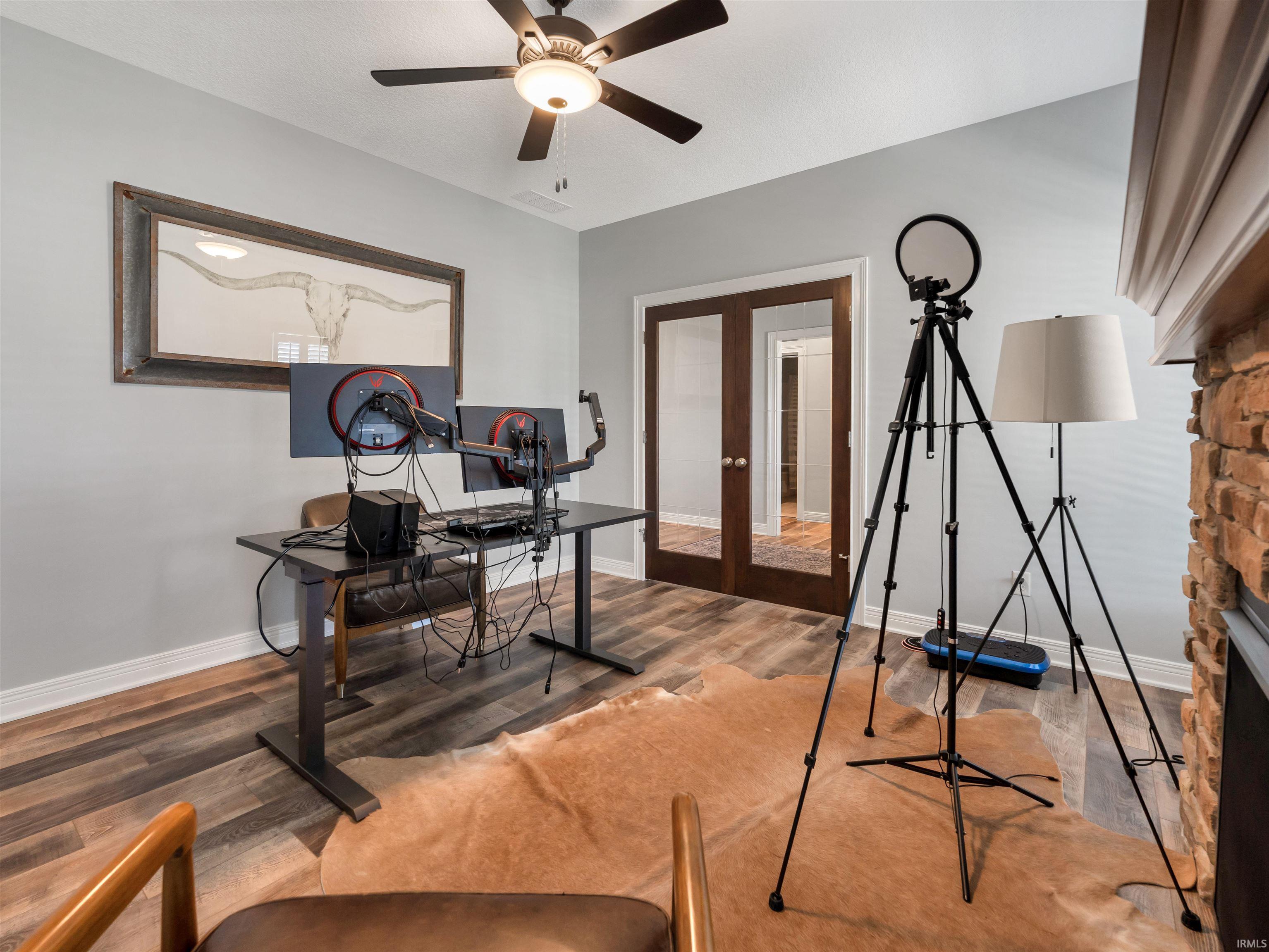 Room featuring wood-finish flooring, light grey wall paint, and a ceiling fan with integrated lighting