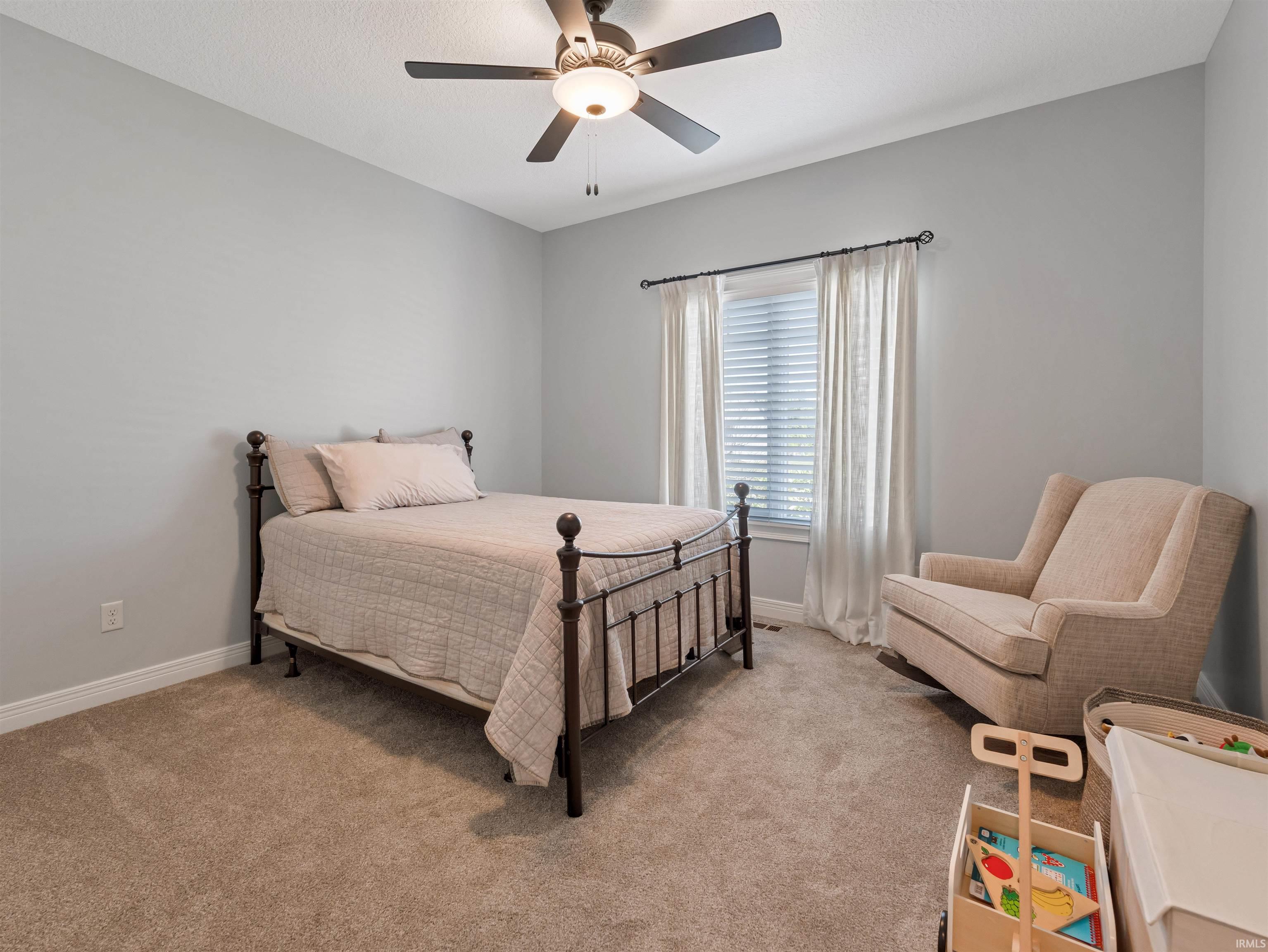Carpeted room featuring a ceiling fan with integrated lighting, a window with blinds and drapes, and neutral wall paint