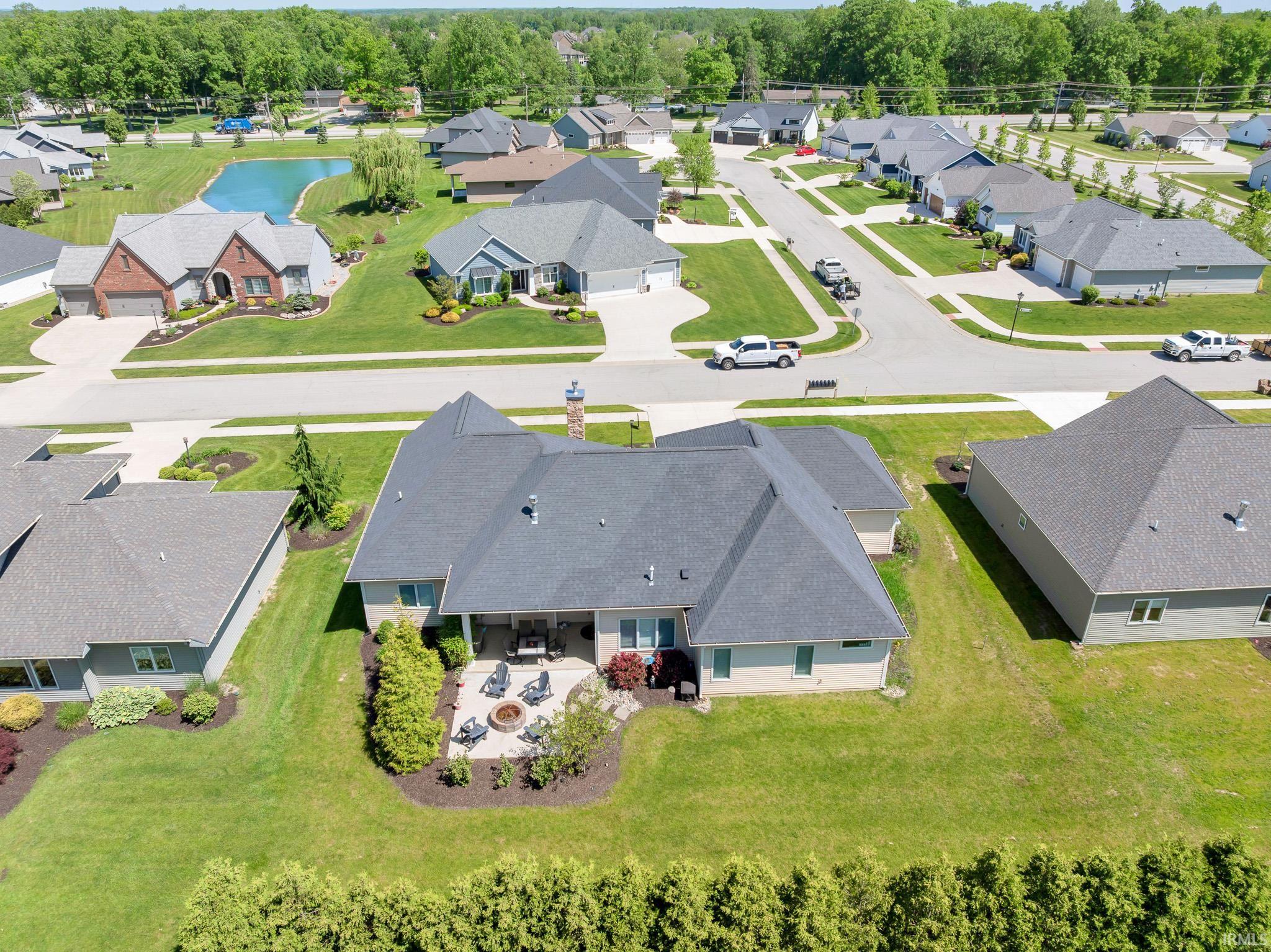 Rear exterior featuring a covered patio, paved fire pit area, and expansive lawn