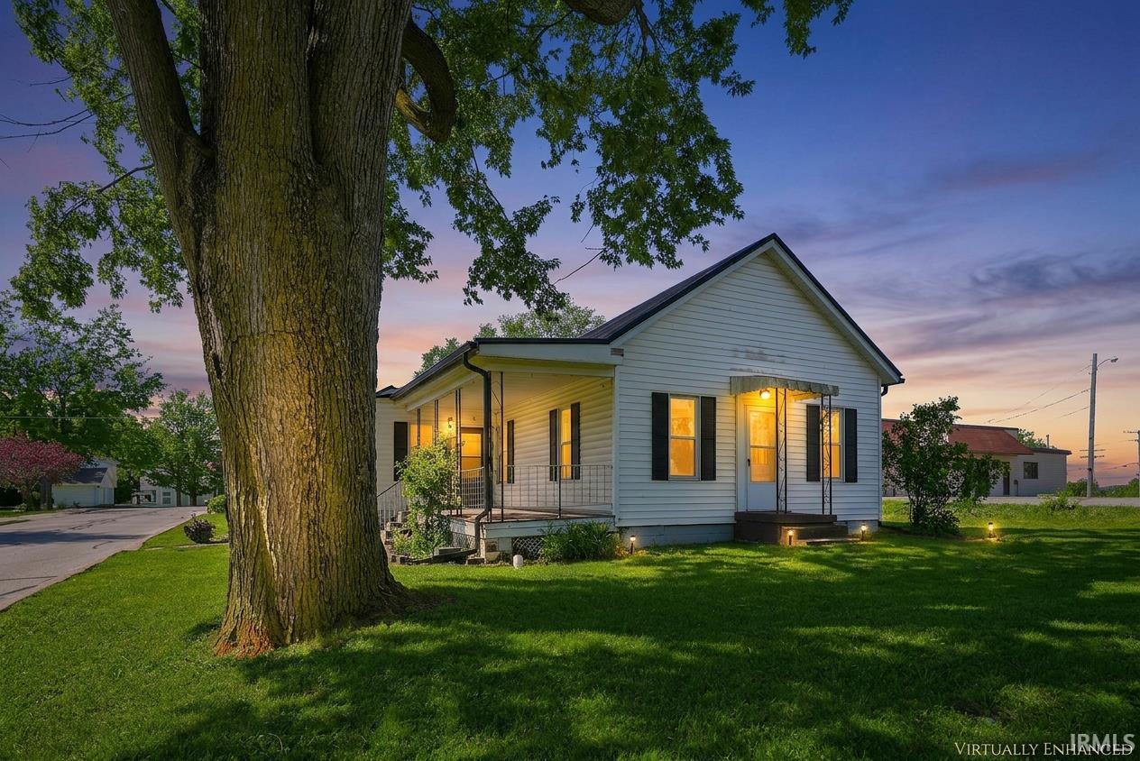 White siding exterior with black shutters and a covered front porch featuring wrought iron railings