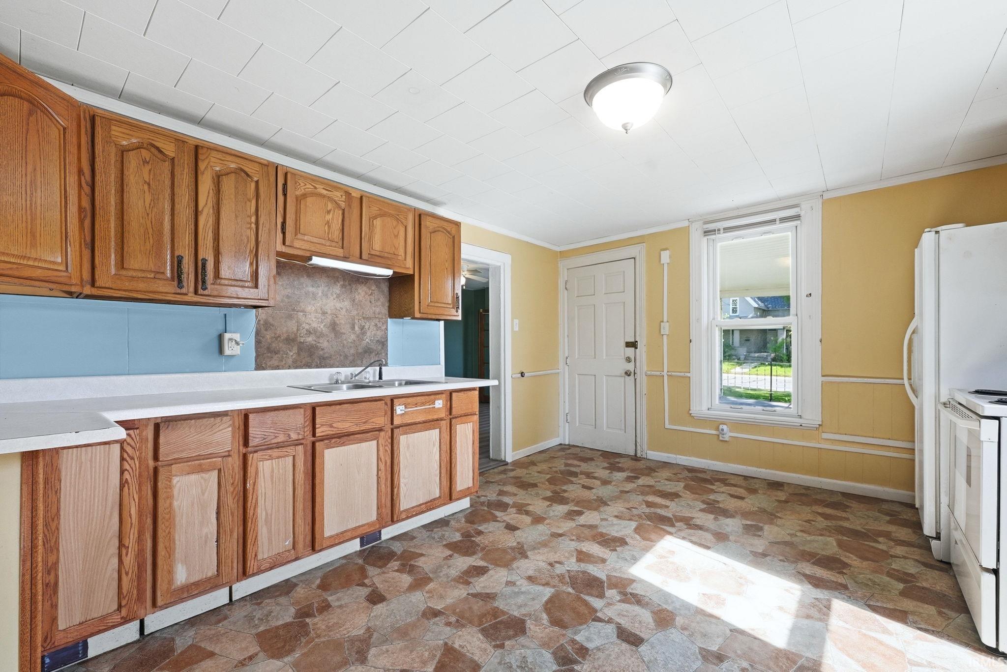 Kitchen featuring wood cabinetry, white countertops, and a stainless steel sink