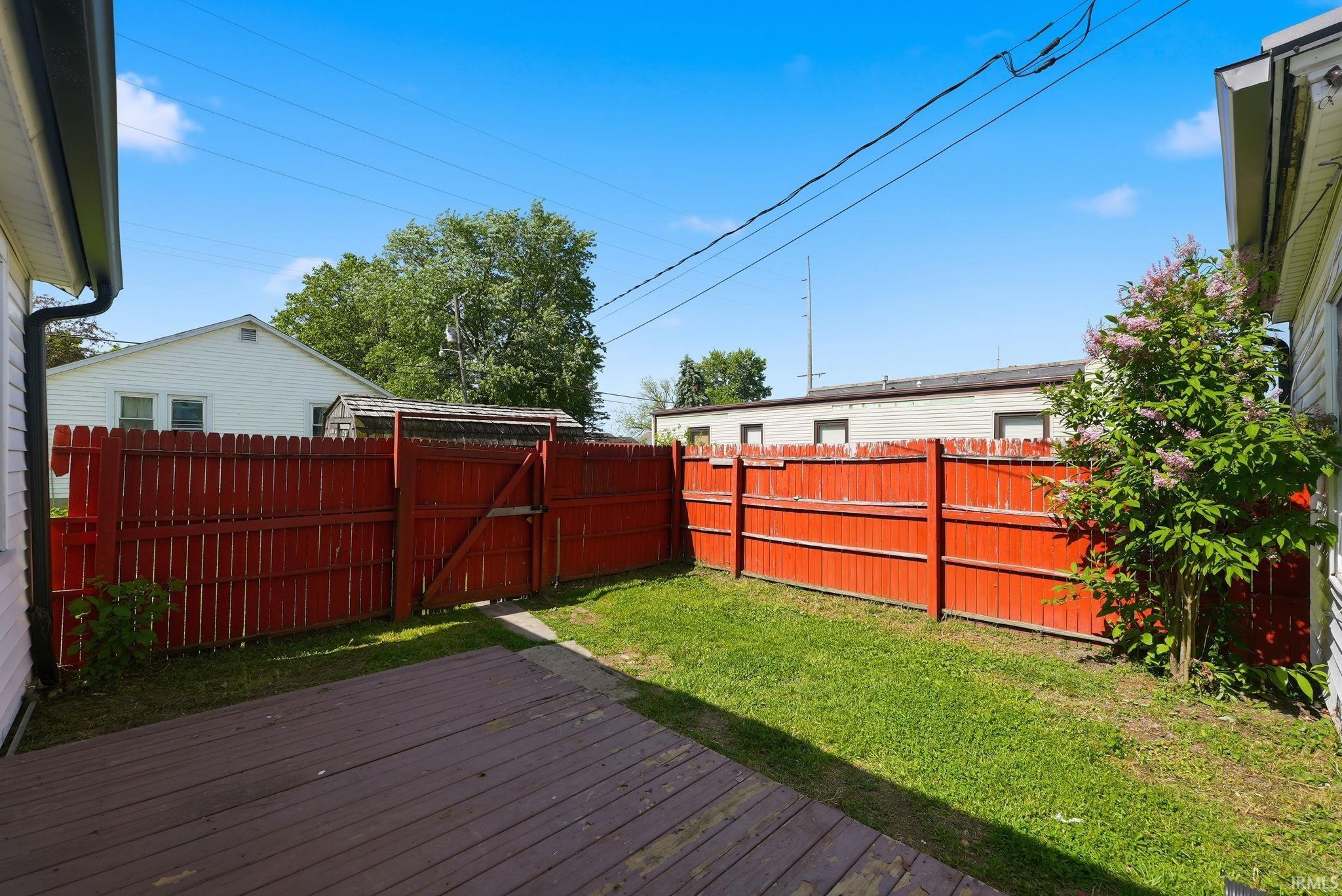 Private backyard featuring a vibrant red privacy fence and a dedicated wooden deck area