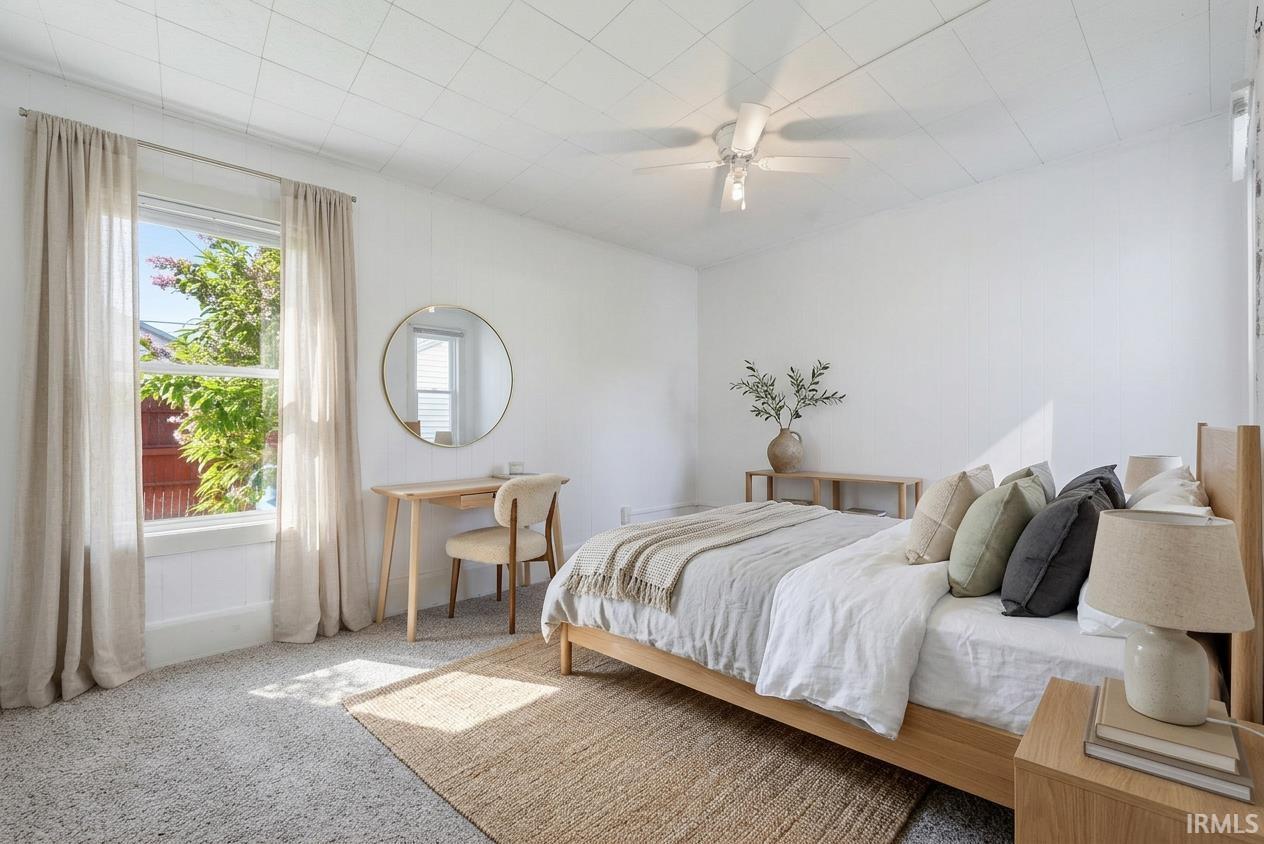 Bedroom featuring neutral wall paint, carpet flooring, a ceiling fan with integrated lighting, and a single window with white trim