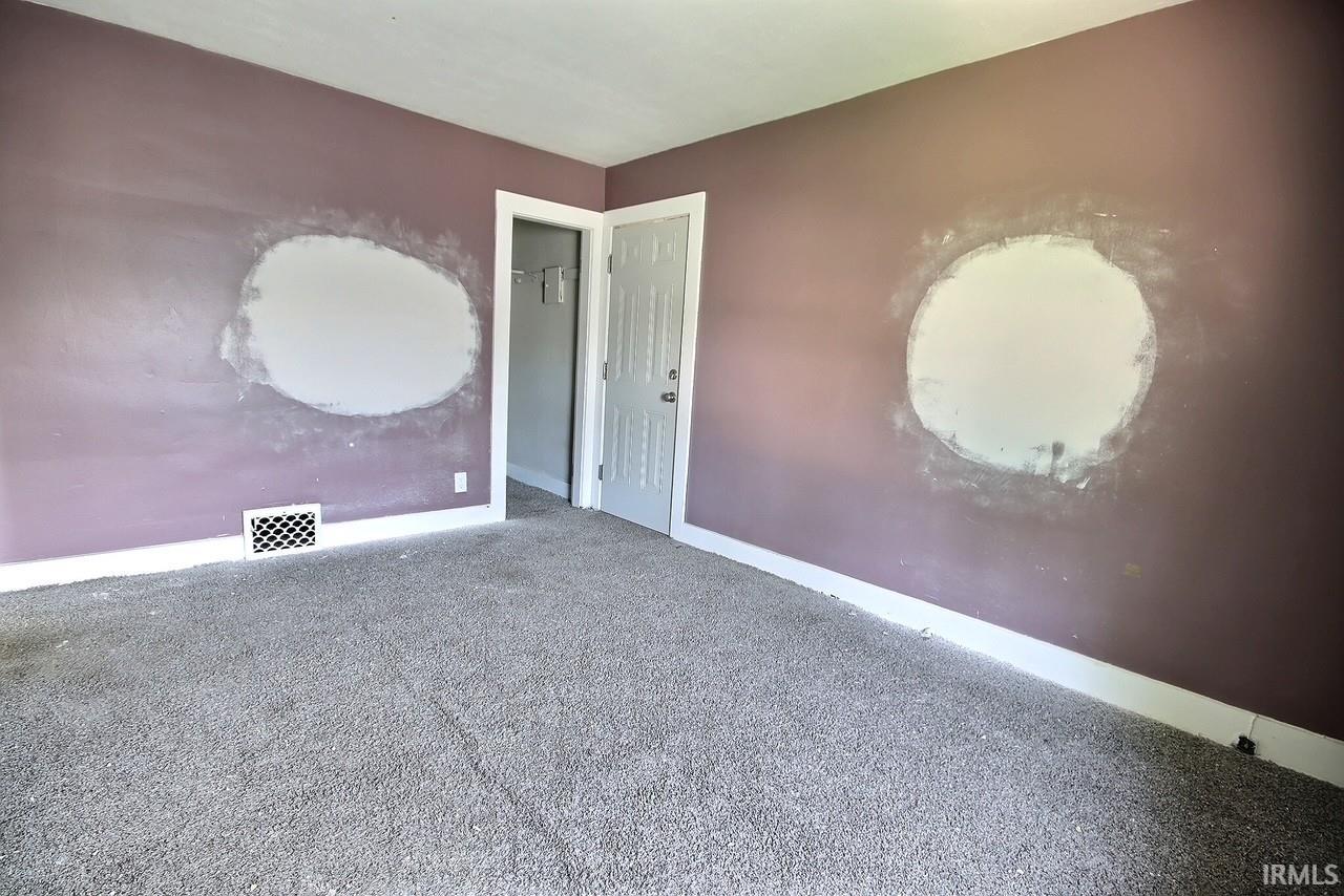 Carpeted room with lavender walls featuring white trim and a white door