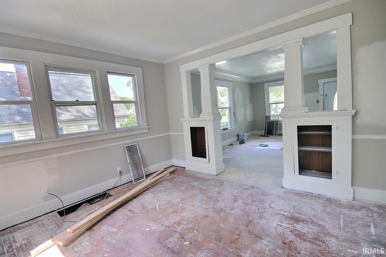Interior space featuring light gray wall paint with white trim, built-in shelving units, and a large multi-pane window