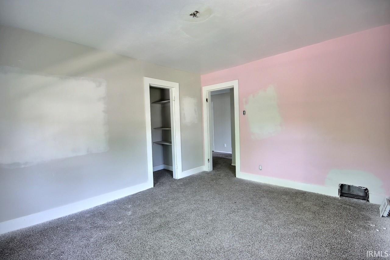 Room featuring textured carpet flooring and walls with varied paint finishes