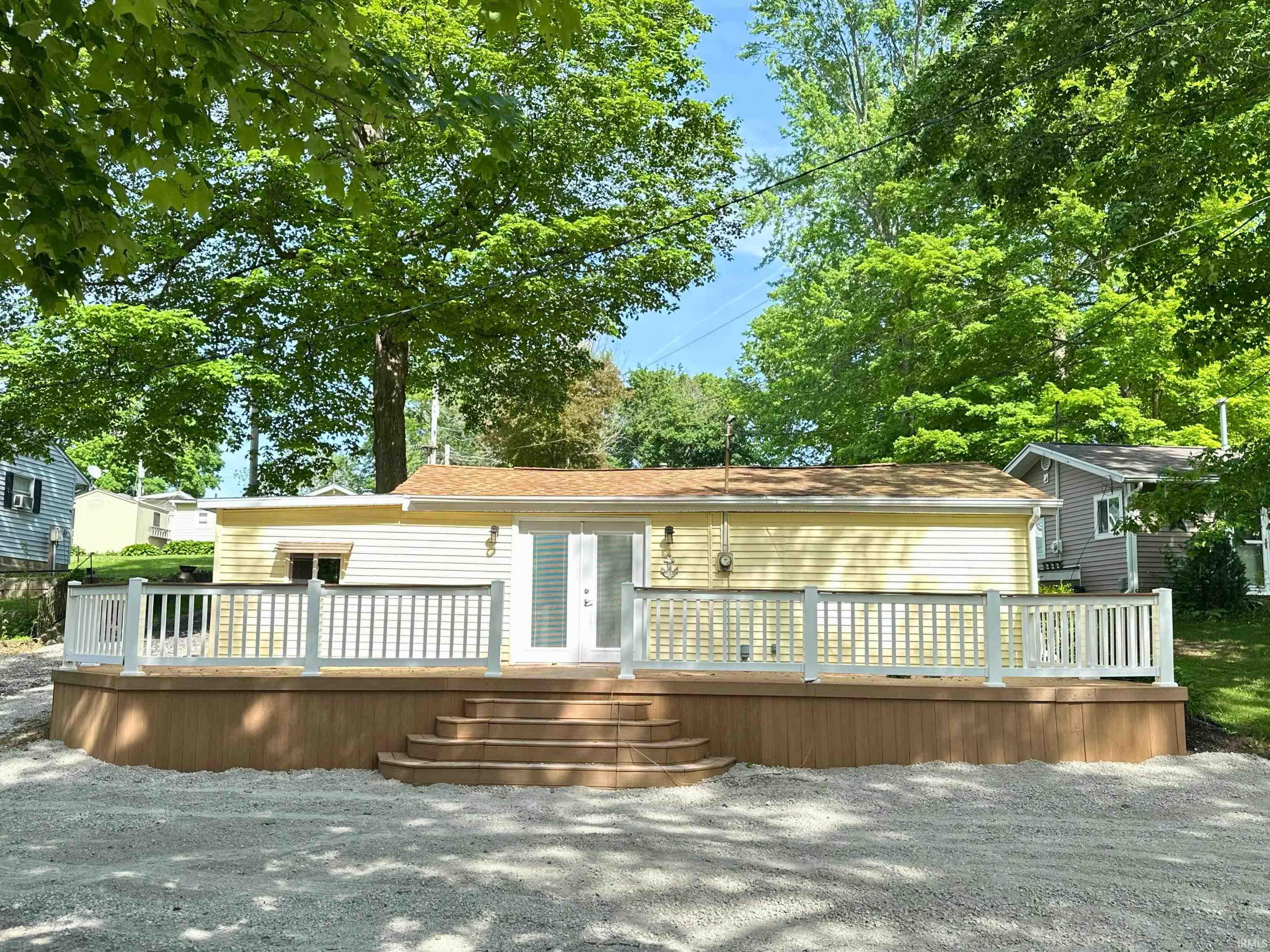 Exterior featuring a large wood-finish deck with white railings, direct access through double doors, and a light yellow siding facade