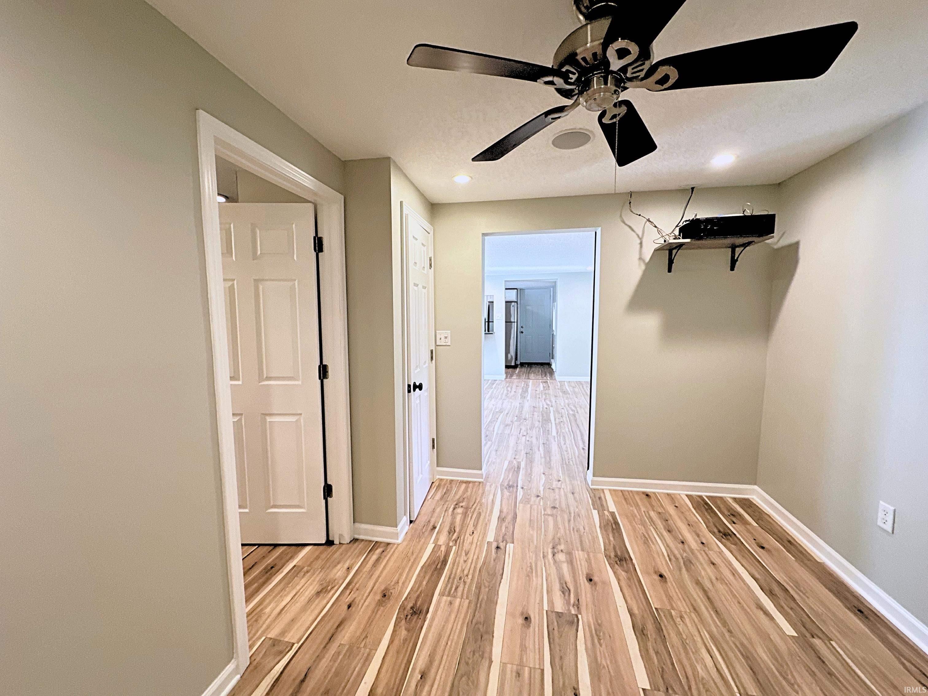 Hardwood flooring throughout, featuring a ceiling fan with integrated lighting, recessed lighting, and crisp white trimwork. In-home surround sound installed in the ceiling.