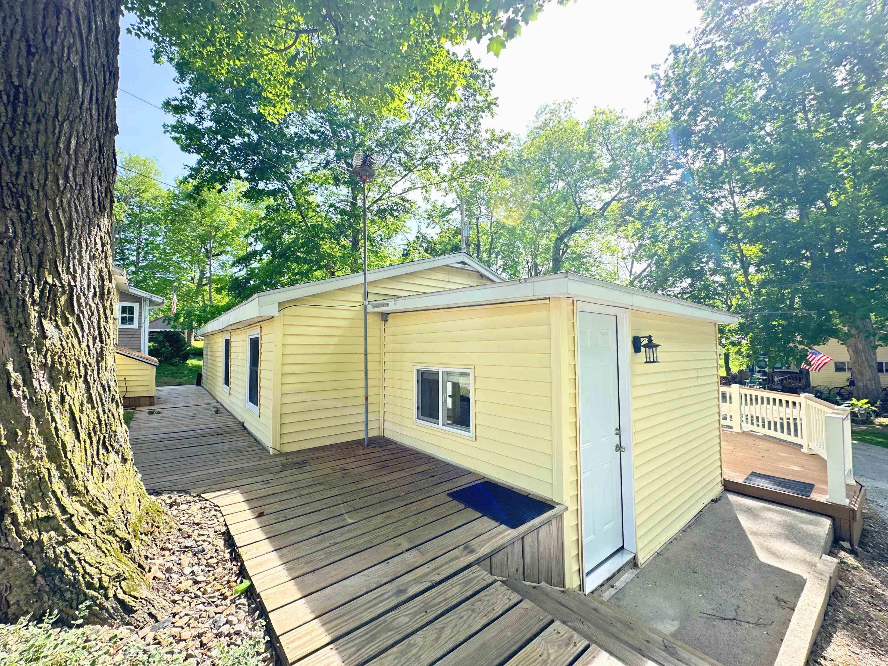 Rear exterior with wood walkway leading to well pump access and shed.