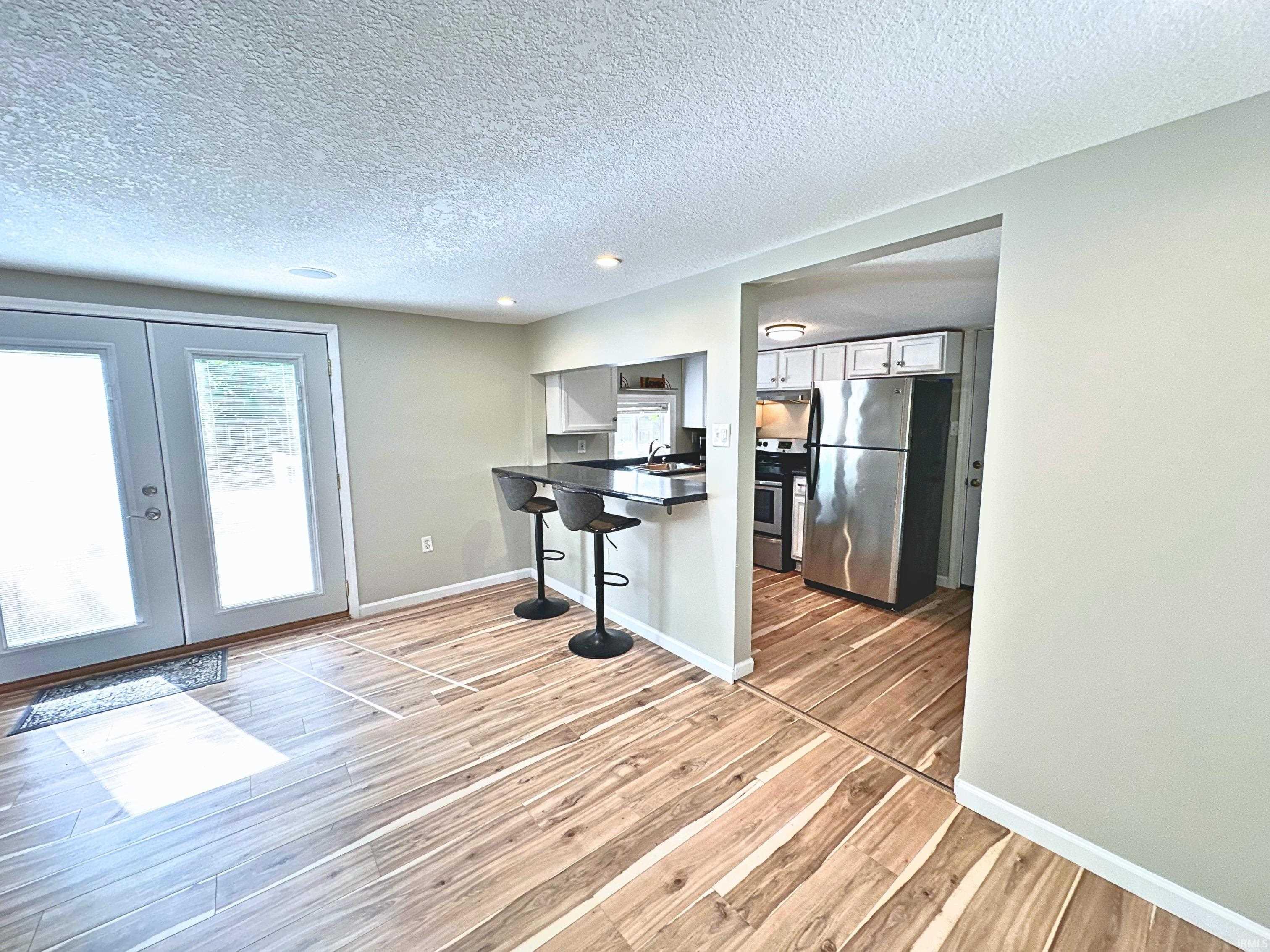 Wood-finish flooring throughout, featuring a kitchen pass-through with a breakfast bar, new white cabinetry, and stainless steel appliances!